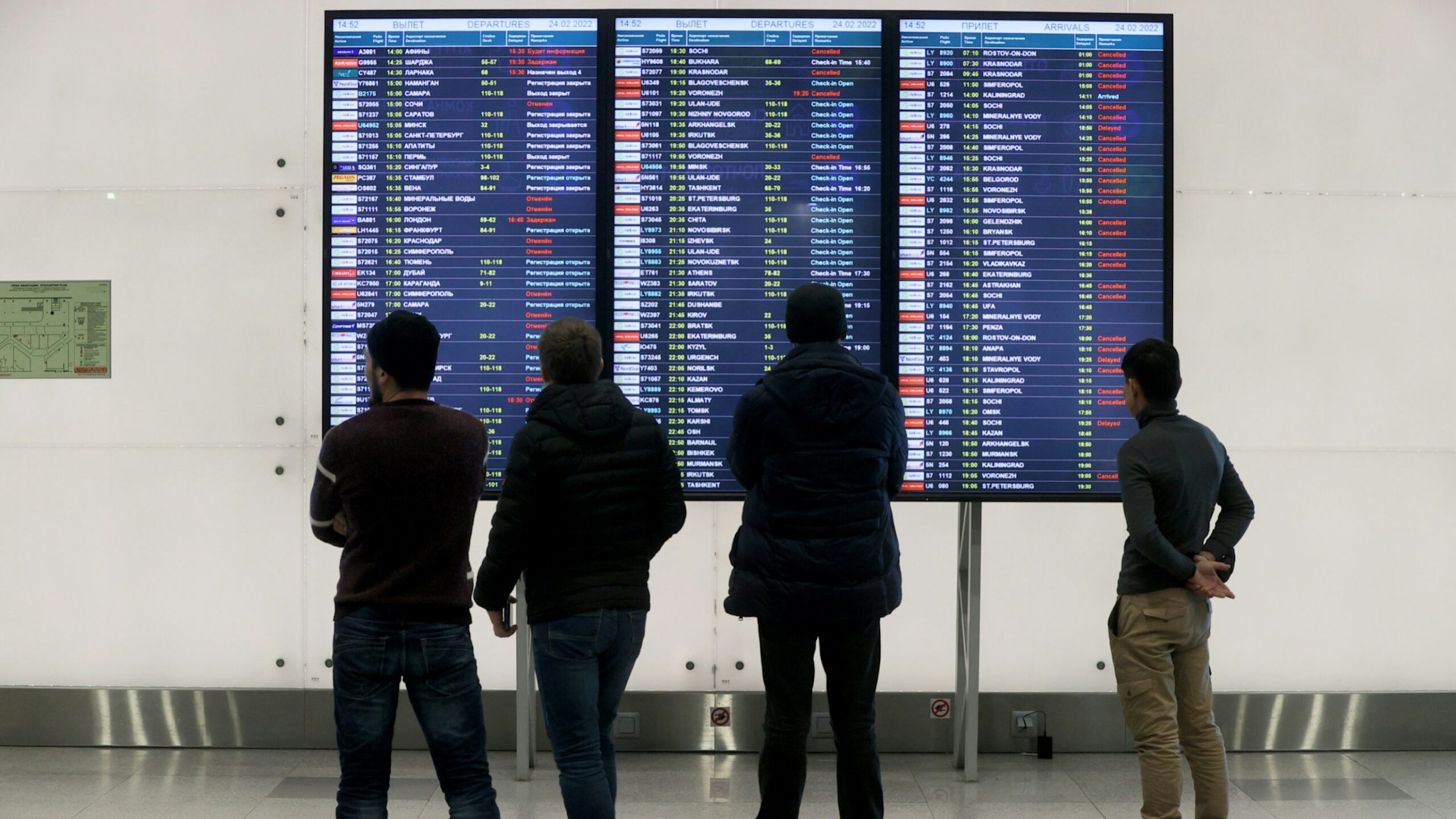 Passengers stand before a departures display board at Domodedovo International Airport.