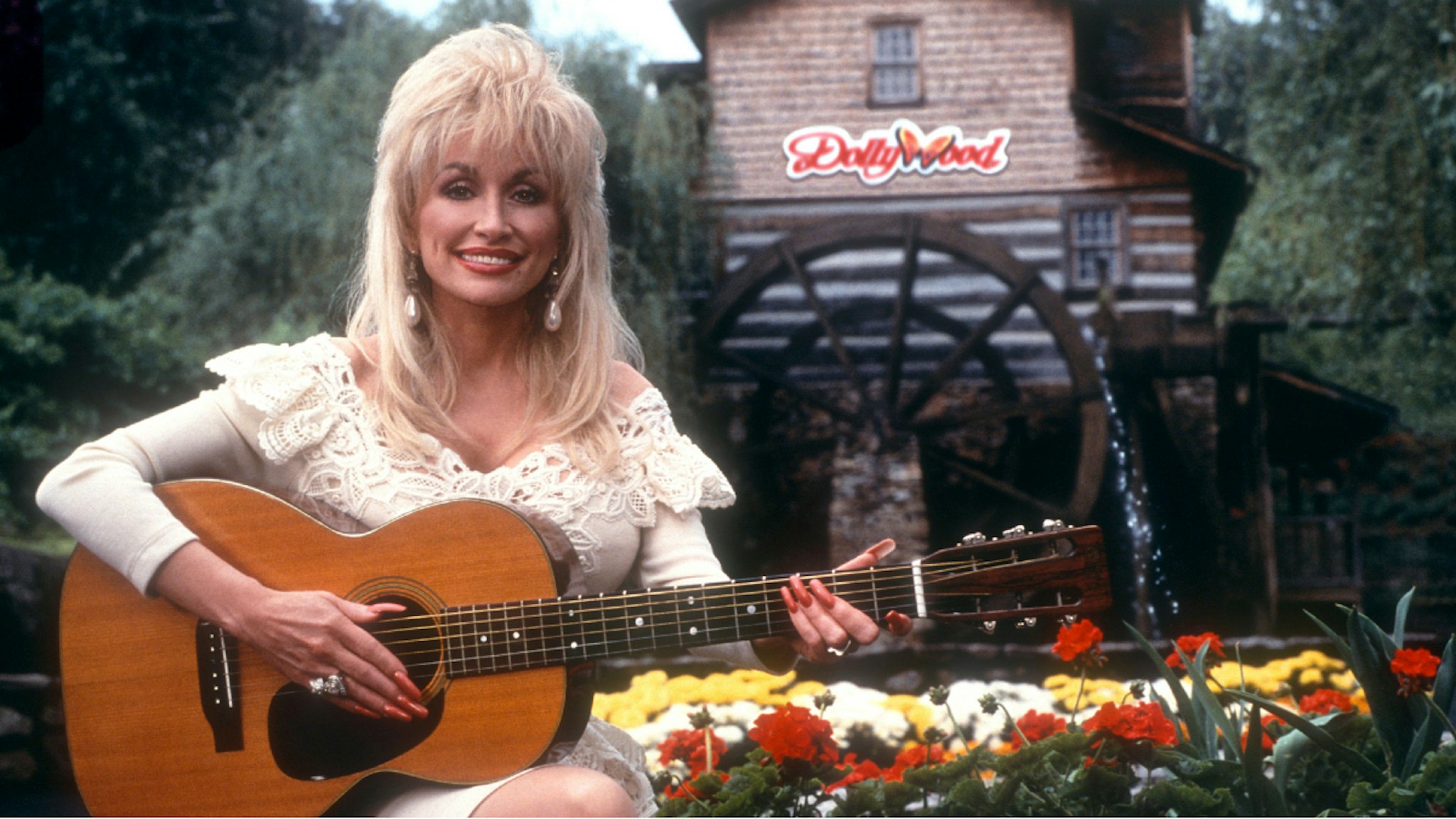 PIGEON FORGE, TN - 1993: American singer and songwriter Dolly Parton poses for a portrait with her guitar at Dollywood circa 1993 in Pigeon Forge, Tennessee.