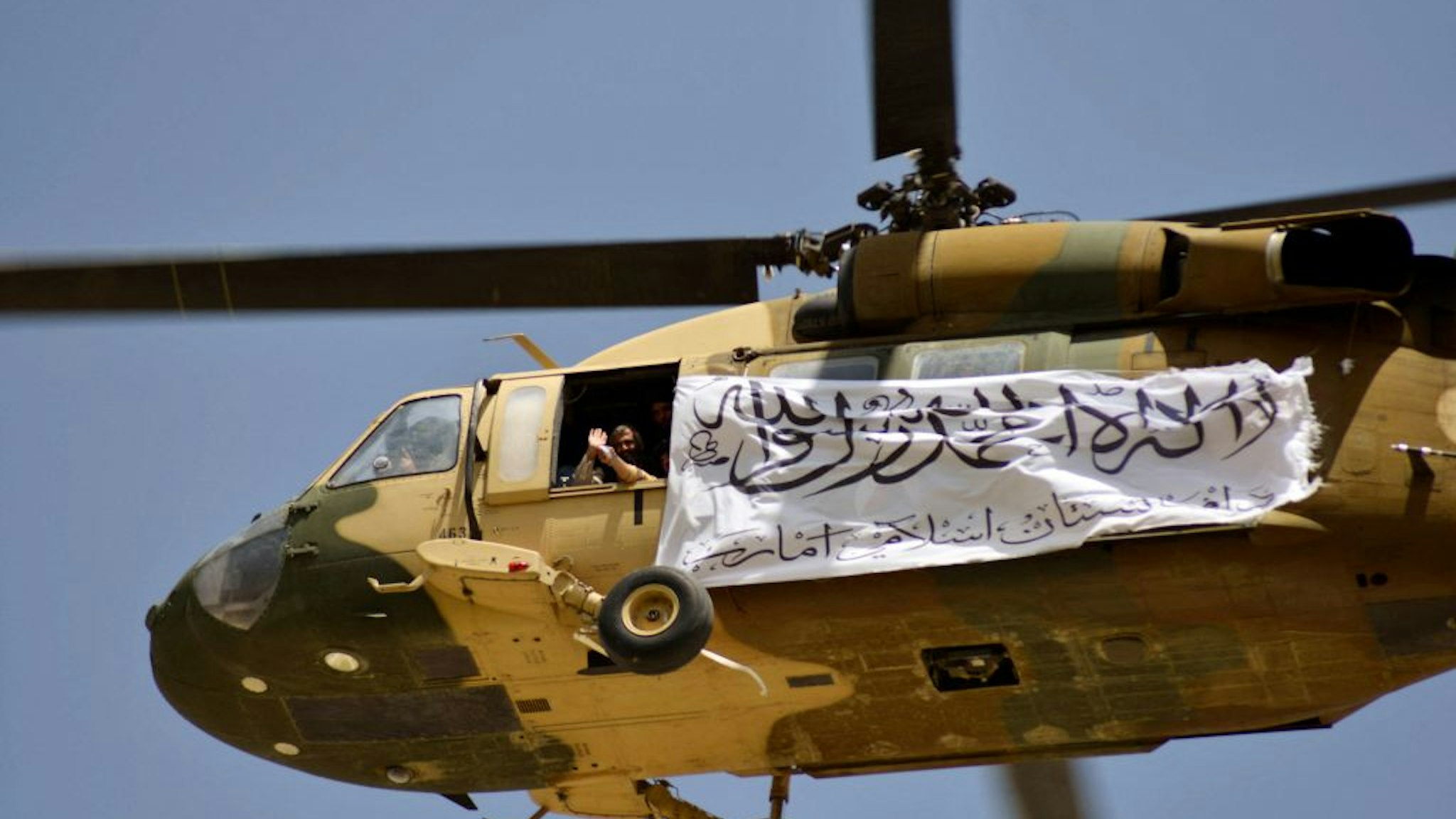 TOPSHOT - A helicopter displaying a Taliban flag flies above Taliban supporters gathered to celebrate the US withdrawal of all its troops out of Afghanistan, in Kandahar on September 1, 2021 following the Talibans military takeover of the country. (Photo by JAVED TANVEER / AFP) (Photo by JAVED TANVEER/AFP via Getty Images)