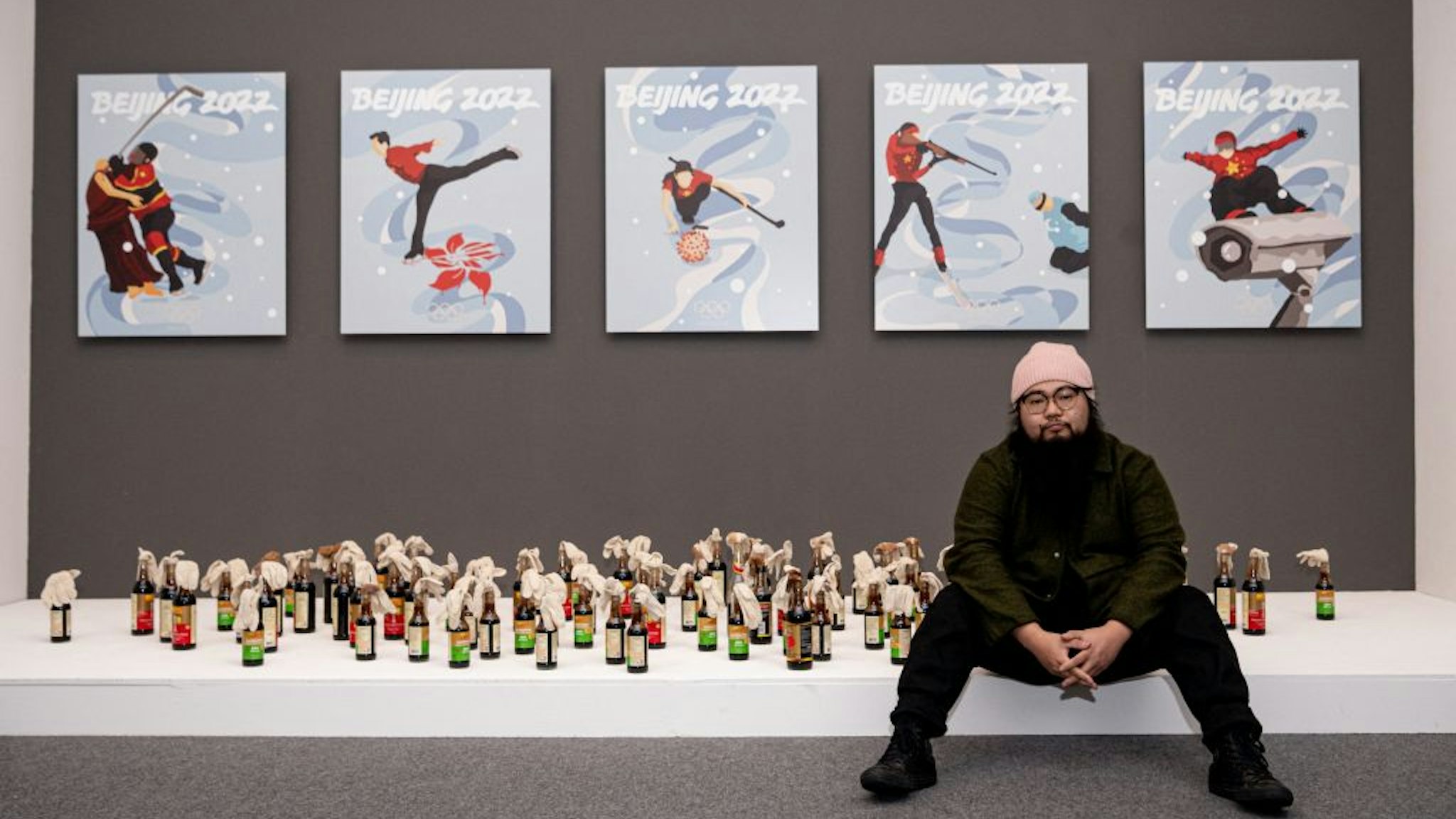 Chinese dissident artist Badiucao poses next to his artwork series inspired by the upcoming 2022 Winter Olympic Games in Beijing, on November 12, 2021 at the exhibition "China is (not) near -- works of a dissident artist", opening at the Santa Giulia museum in Brescia, Lombardy.