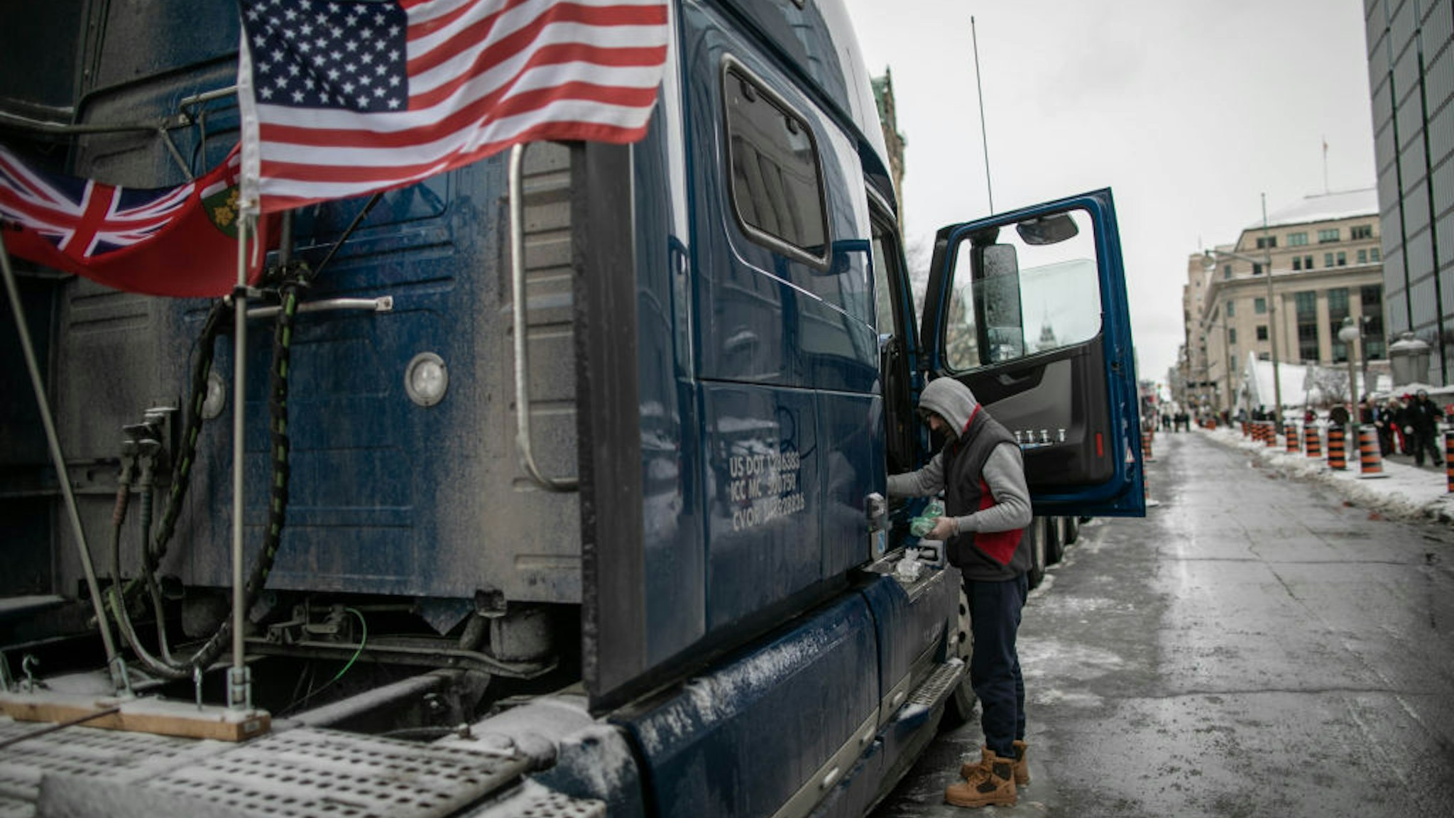 A supporters of the freedom convoy passes by parked trucks in front of the parliament hill as truckers continue their rally against coronavirus (COVID-19) measures and vaccine mandate in Ottawa, Canada on February 3, 2022.