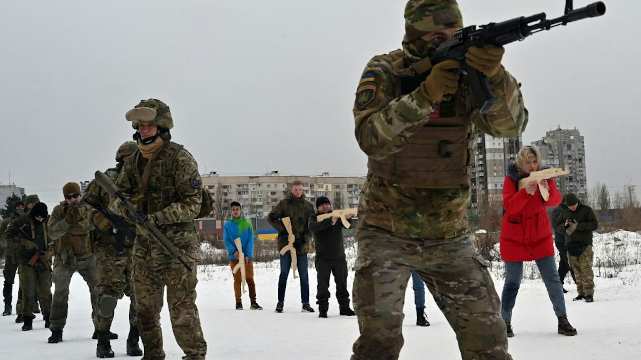 A military instructor teaches civilians holding wooden replicas of Kalashnikov rifles, as they take part in a training session at an abandoned factory in the Ukrainian capital of Kyiv on February 6, 2022.