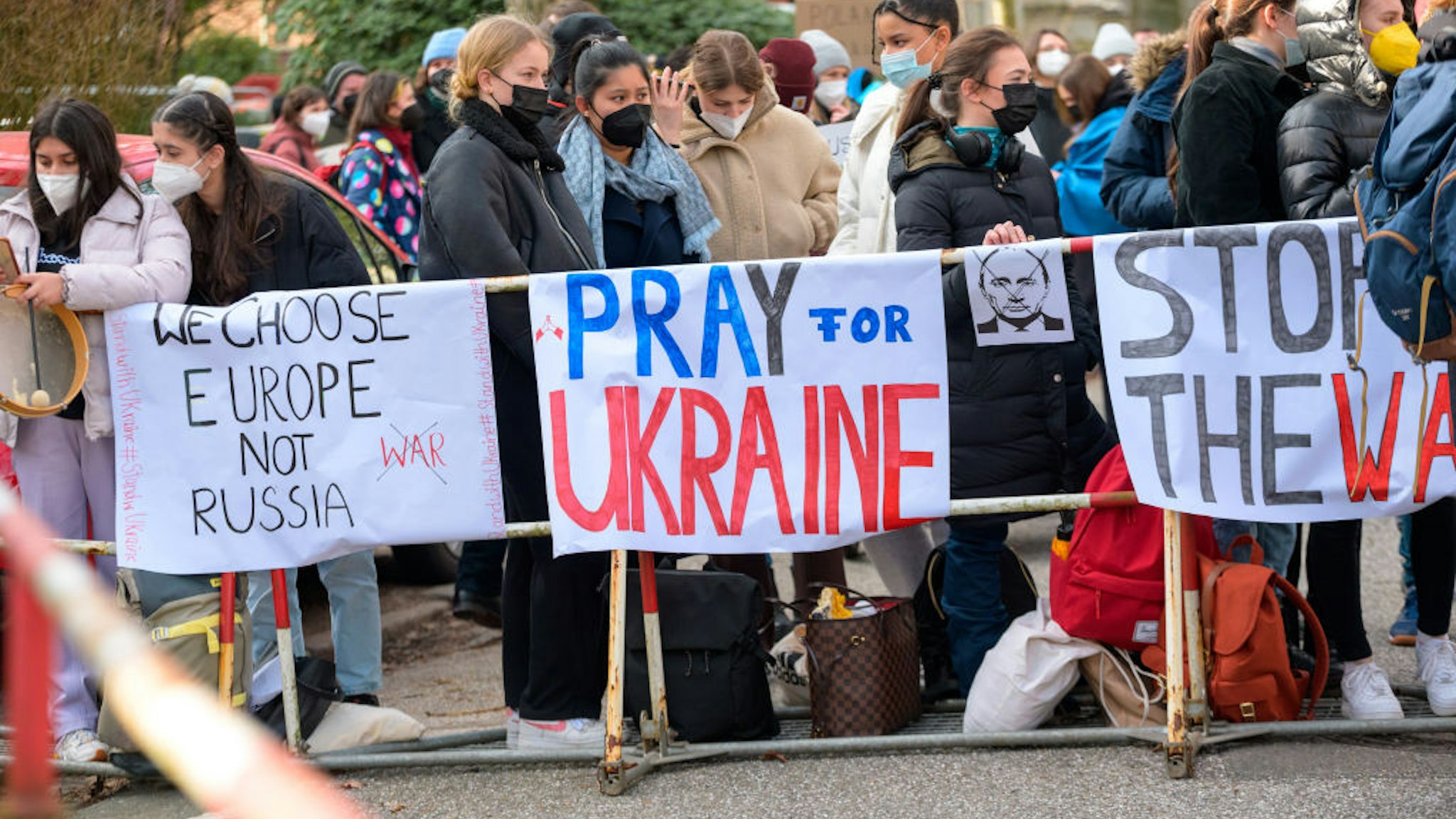 Participants of a protest against the Russian invasion of Ukraine stand in front of the Russian Consulate General with flags and posters reading "We choose Europe not Russia", "Pray for Ukraine" and "Stop the war".