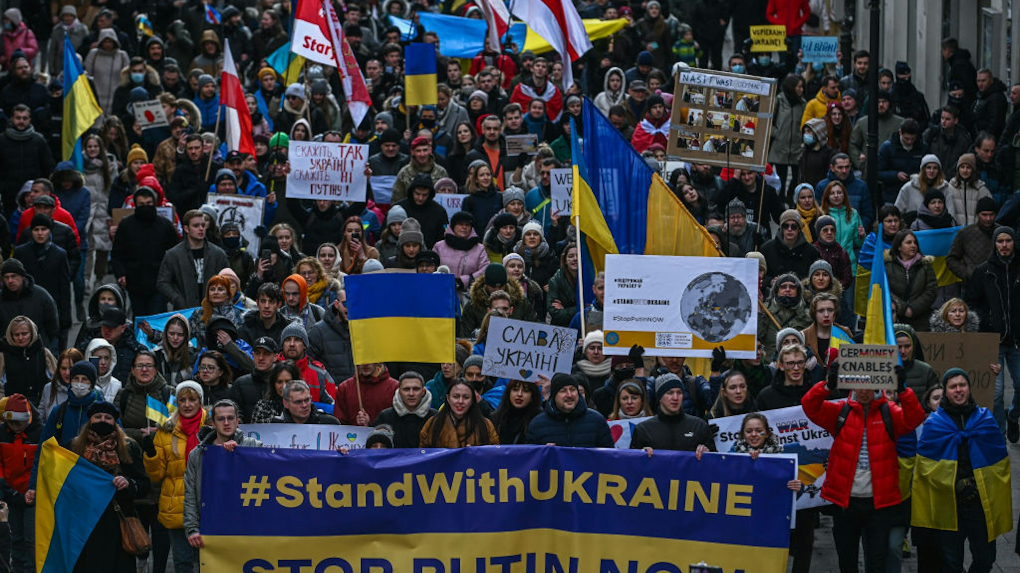 Ukrainians hold banners and Ukrainian national flags during a protest for peace in Ukraine at Krakow's UNESCO listed Main Square on February 20, 2022 in Krakow, Poland