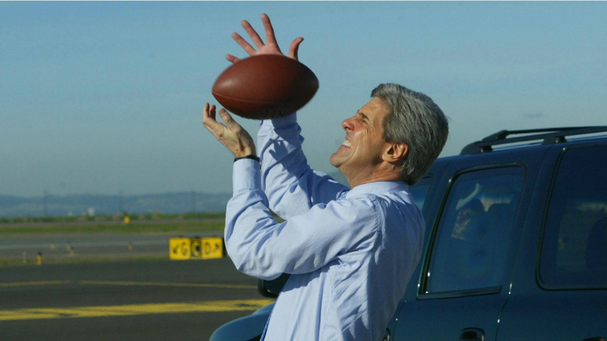 OAKLAND, CA - FEBRUARY 28: U.S. Senator John Kerry (D-MA) plays football on the tarmac February 28, 2004 in Oakland, California. Democratic presidential candidate Kerry is scheduled to appear at a town hall-style meeting in Brooklyn, New York, this evening.