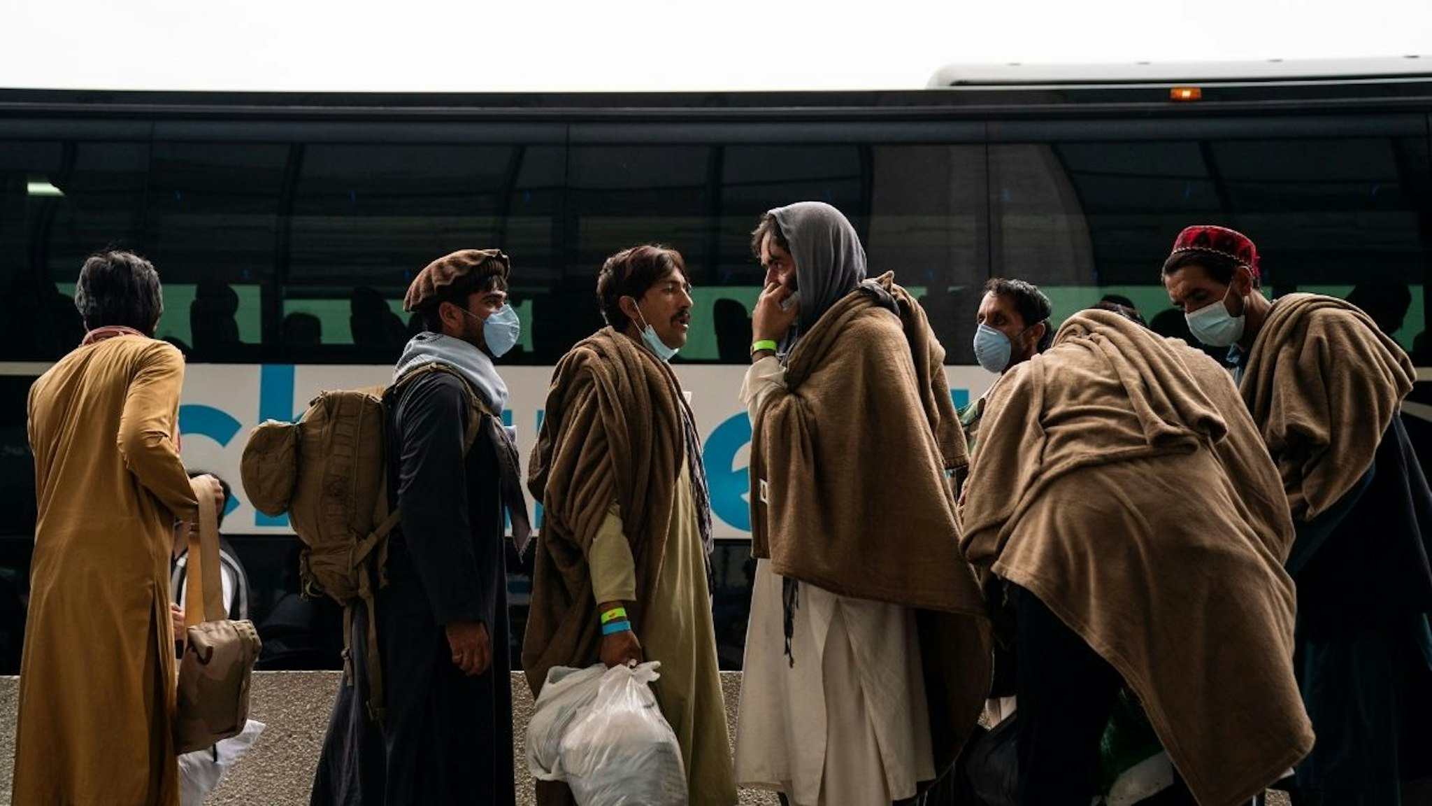Evacuees who fled Afghanistan walk through the terminal to board buses that will take them to a processing center, at Dulles International Airport on Tuesday, Aug. 31, 2021.