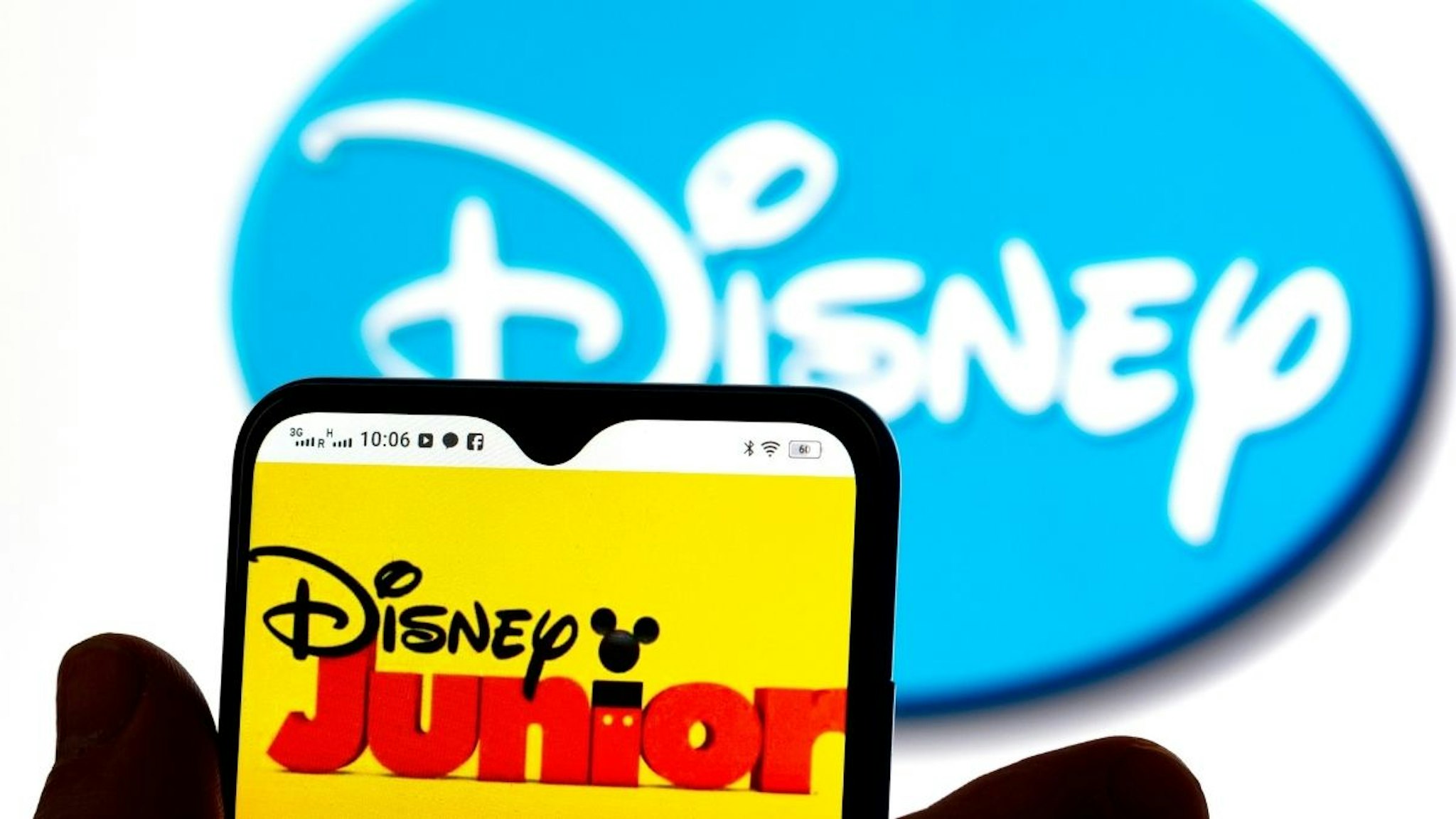 In this photo illustration, the Disney Junior logo is seen displayed on a smartphone screen with a Disney logo in the background.