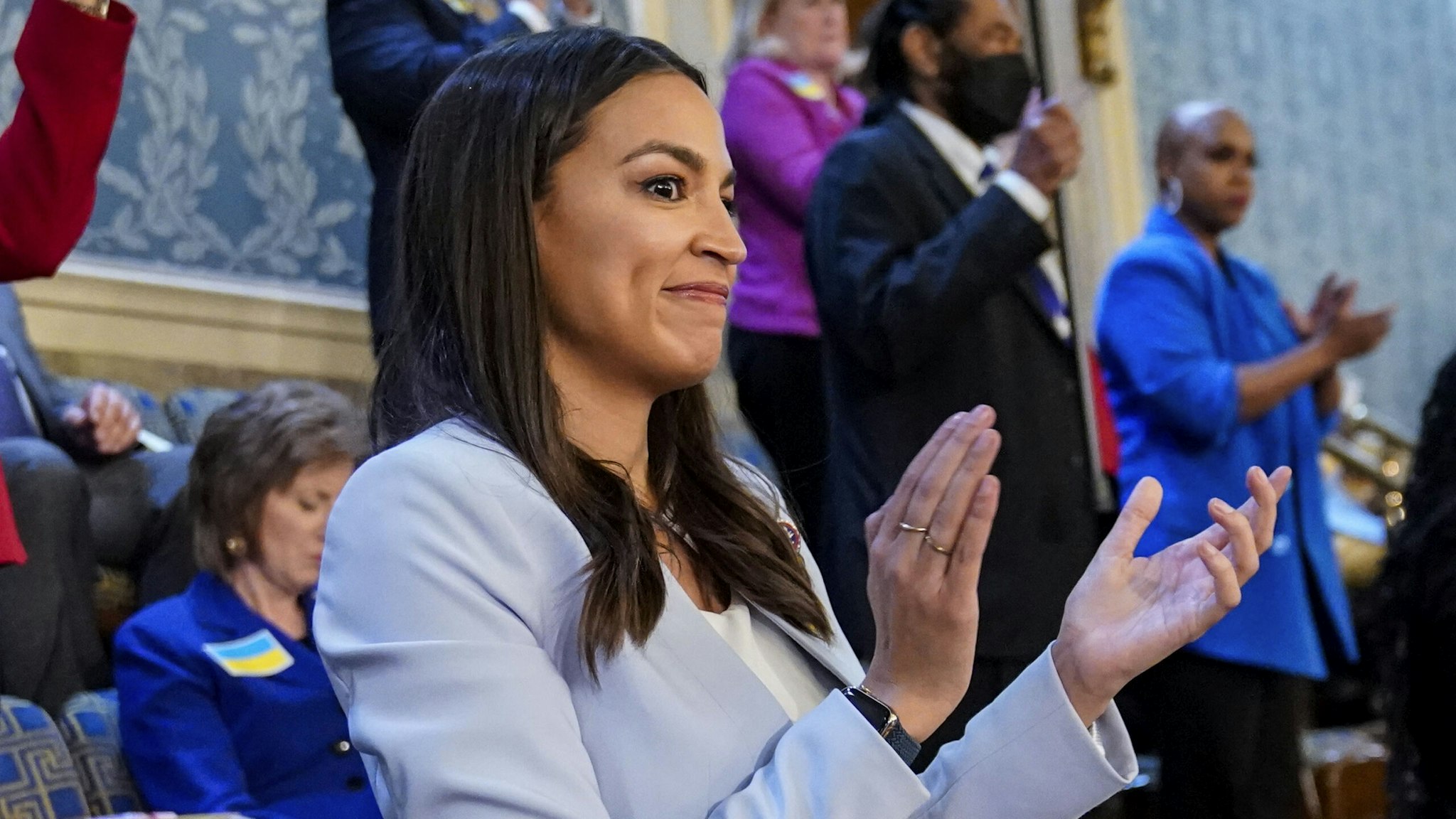 WASHINGTON, DC - MARCH 01: U.S. Rep. Alexandria Ocasio-Cortez (D-NY) claps as U.S. President Joe Biden delivers the State of the Union address flanked by Vice President Kamala Harris and House Speaker Nancy Pelosi (D-CA) during a joint session of Congress in the U.S. Capitol’s House Chamber on March 01, 2022 in Washington, DC. During his first State of the Union address, Biden spoke on his administration’s efforts to lead a global response to the Russian invasion of Ukraine, efforts to curb inflation and bringing the country out of the COVID-19 pandemic.