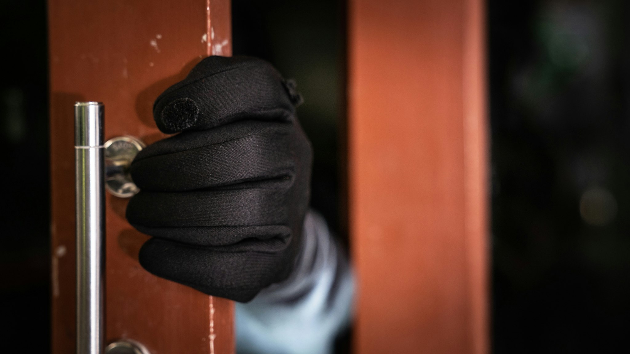 dangerous masked burglar with crowbar breaking into a victim's home door,Home insurance concept - stock photo