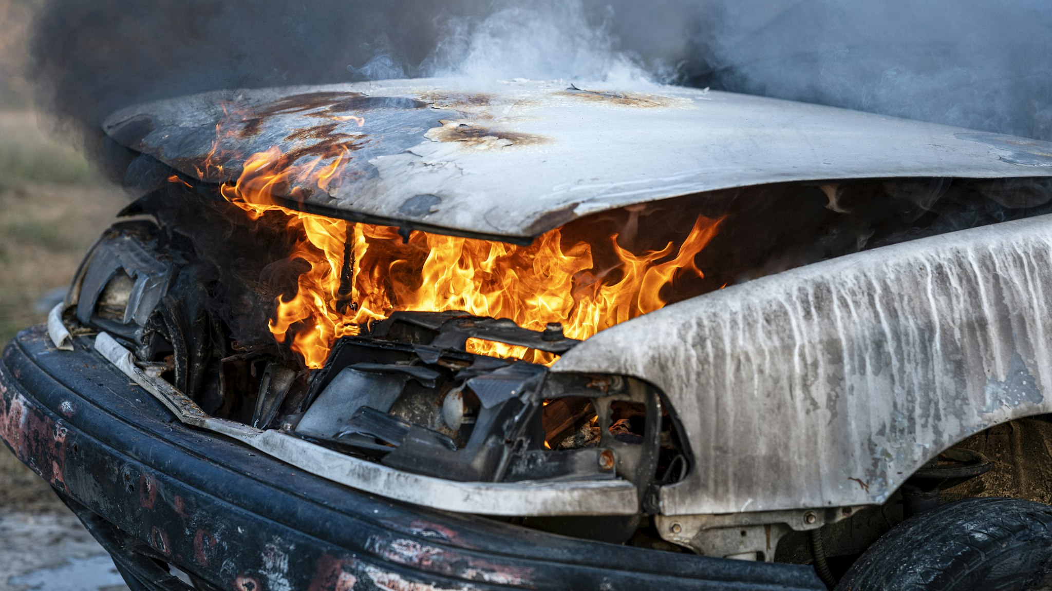 Close-up of burning car engine after a frontal crash collision on the roadside with flame and smoke. - stock photo
