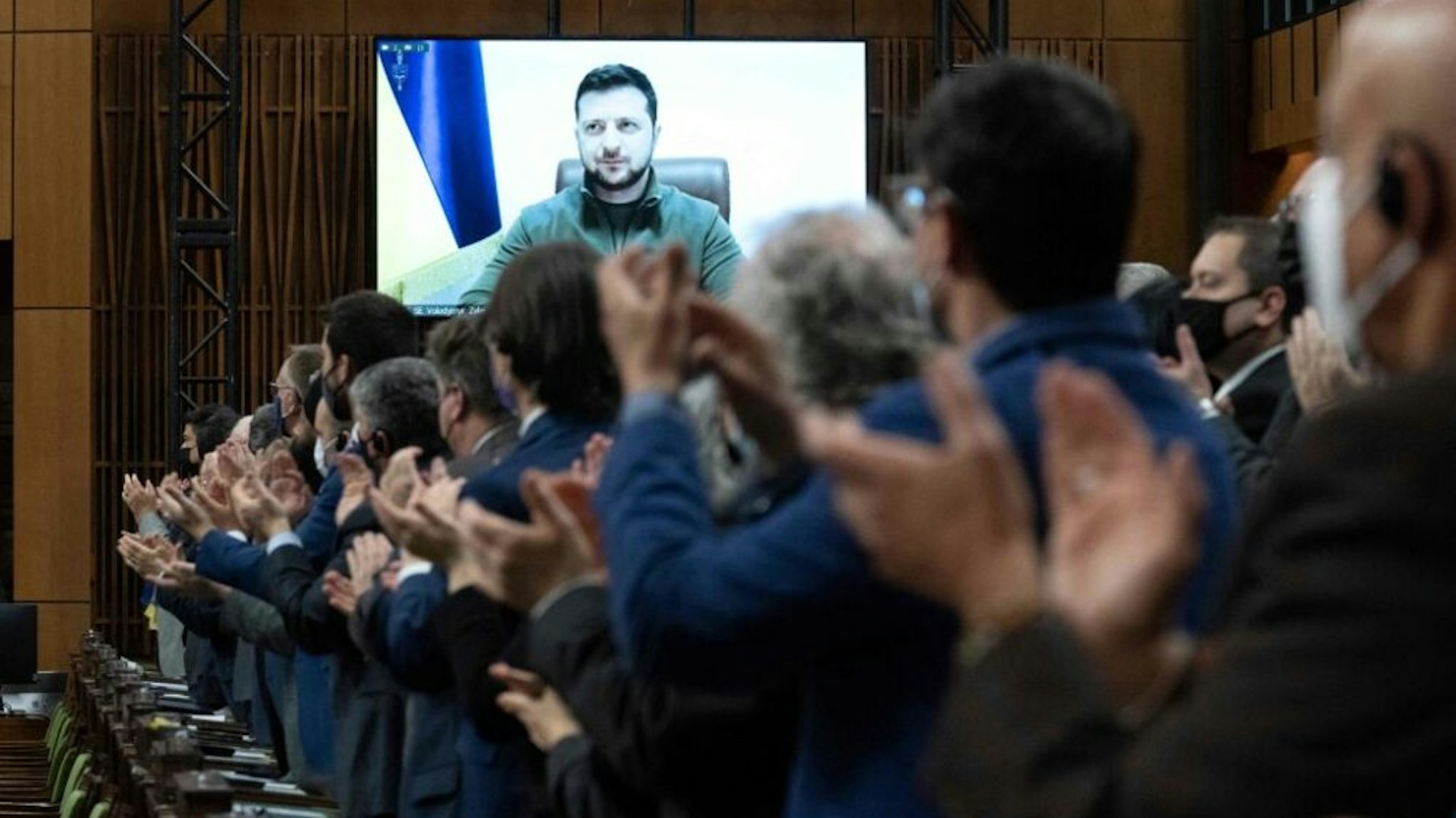 Canadian Members of Parliament and invited guests applaud Ukrainian President Volodymyr Zelensky before virtually addressing the Canadian Parliament, March 15, 2022 in Ottawa.