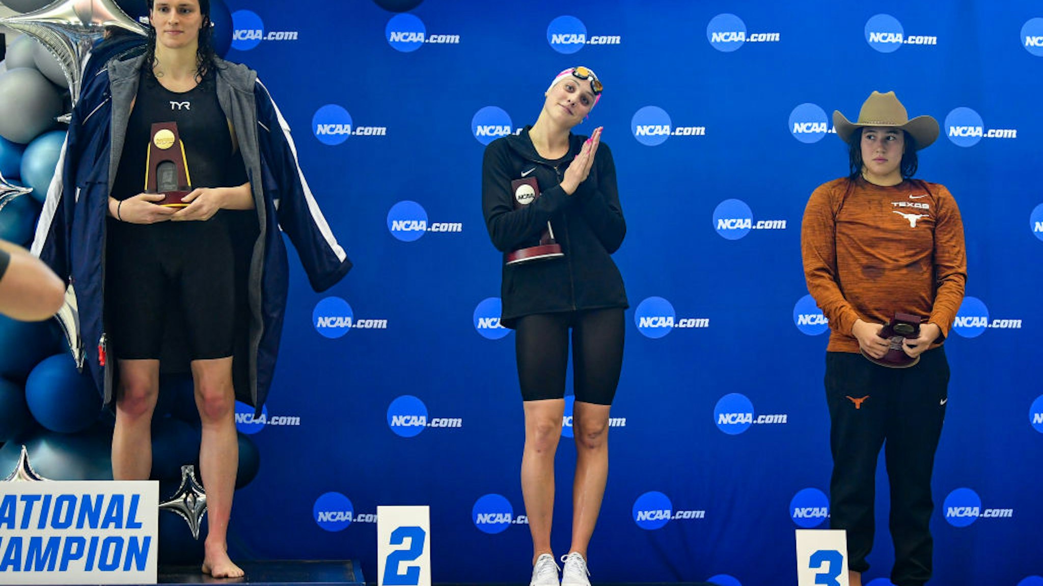 University of Pennsylvania swimmer Lia Thomas accepts the winning trophy for the 500 Freestyle finals as second place finisher Emma Weyant and third place finisher Erica Sullivan watch during the NCAA Swimming and Diving Championships on March 17th, 2022 at the McAuley Aquatic Center in Atlanta Georgia.