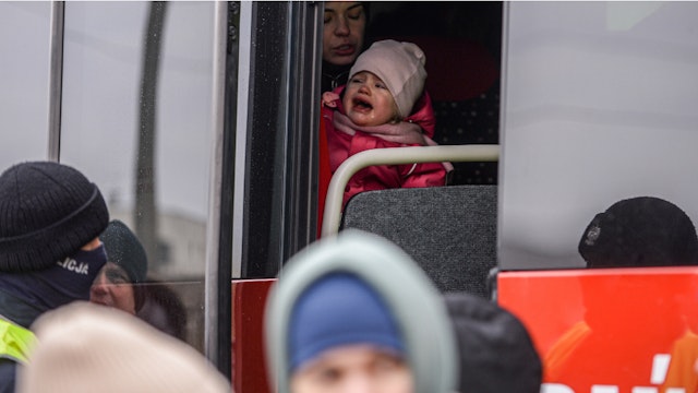 MEDYKA, POLAND - MARCH 04: A baby who fled the war in Ukraine cries on the mother's lap as they wait for a bus to departure from the Polish Ukrainian border on March 04, 2022 in Medyka, Poland. 0 from leaving and calling on them to fight.