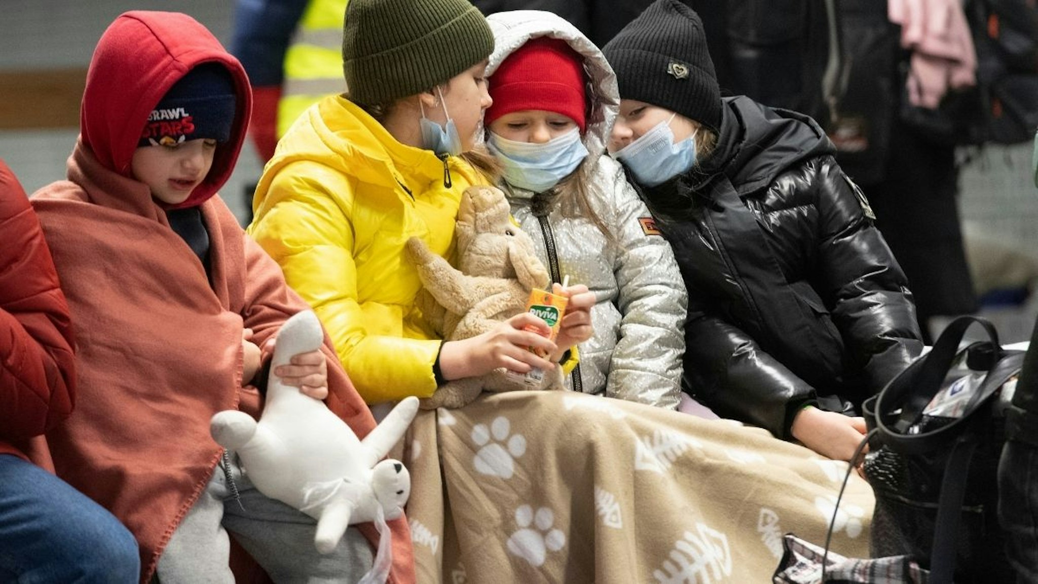 Wrapped in blankets, these children from the Ukrainian war zone sit on a bench in Berlin's main train station.
