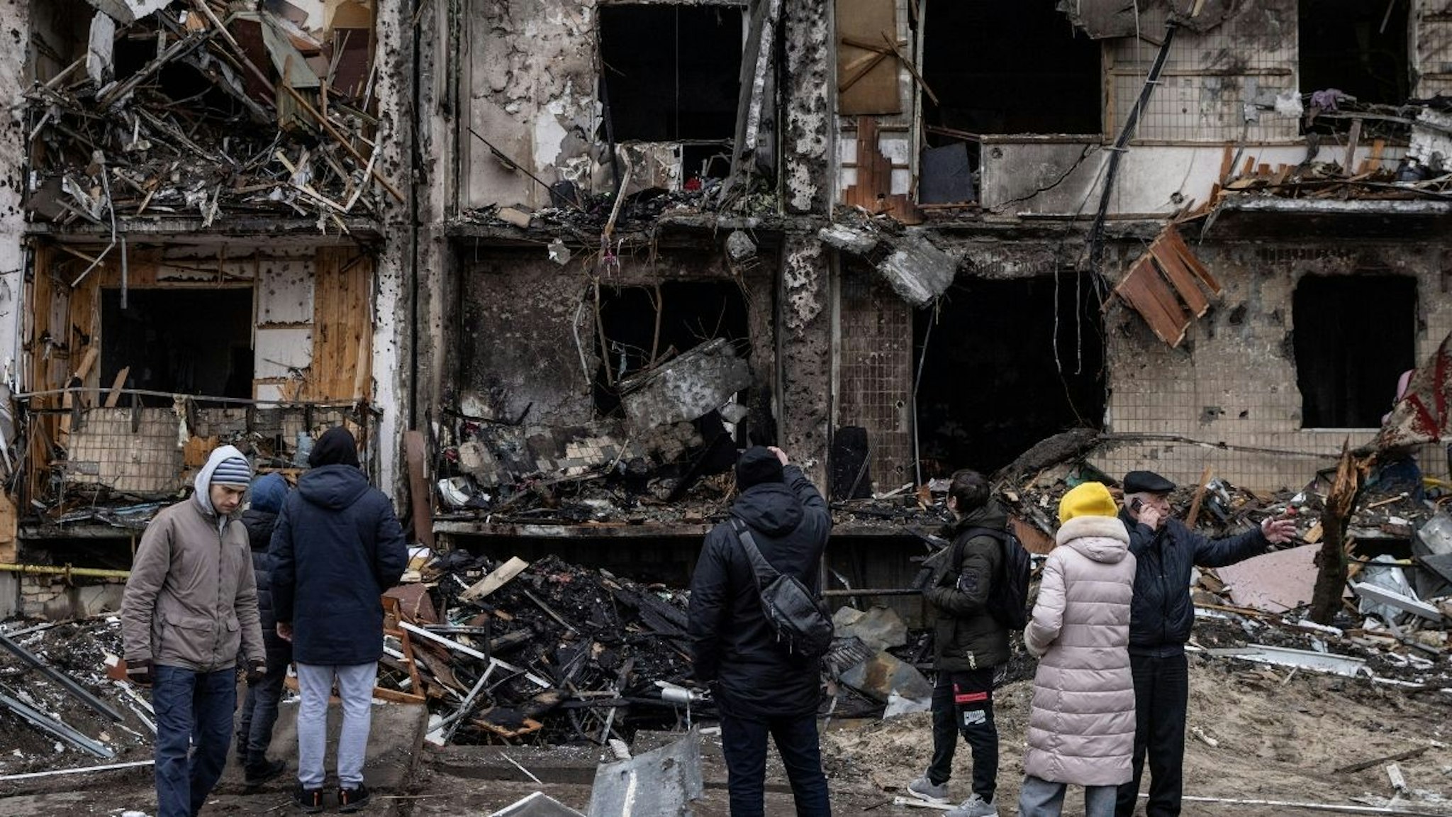 People look at the exterior of a damaged residential block hit by an early morning missile strike on February 25, 2022 in Kyiv, Ukraine. Yesterday, Russia began a large-scale attack on Ukraine, with Russian troops invading the country from the north, east and south, accompanied by air strikes and shelling.