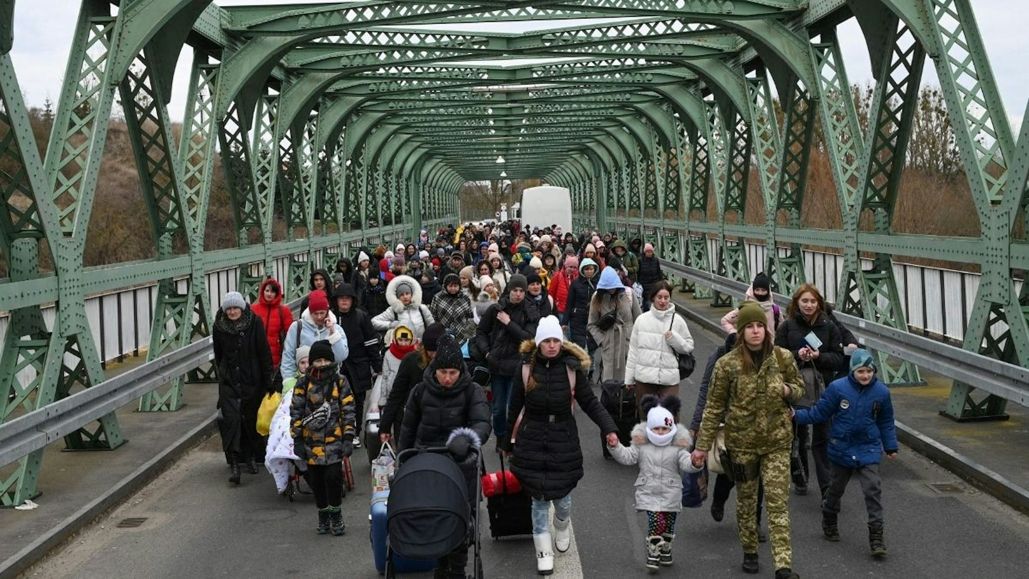 Ukrainian refugees walk a bridge at the buffer zone with the border with Poland in the border crossing of Zosin-Ustyluh, western Ukraine on March 6, 2022.