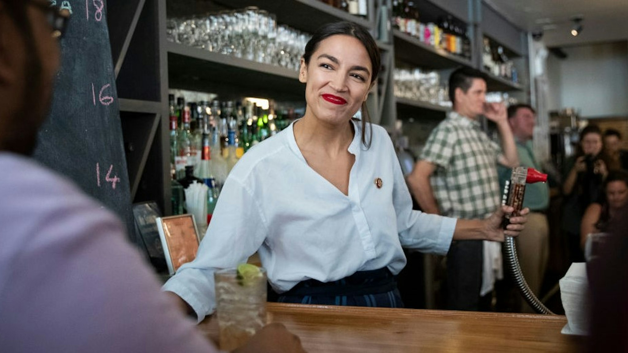 NEW YORK, NY - MAY 31: U.S. Rep. Alexandria Ocasio-Cortez (D-NY) works behind the bar at the Queensboro Restaurant, May 31, 2019 in the Queens borough of New York City. Ocasio-Cortez participated in an event to raise awareness for the One Fair Wage campaign, which calls to raise the minimum wage for tipped workers to a full minimum wage at the federal level. (Photo by