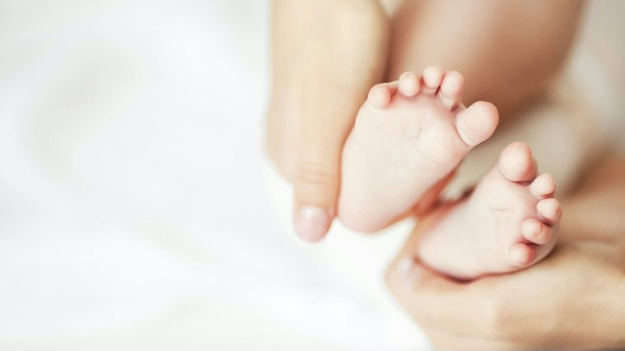Happy Feet - stock photo Parent holding the feet of a newborn baby. PhotoBeaM via Getty Images
