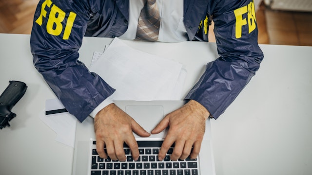A senior FBI agent uses a laptop in the office