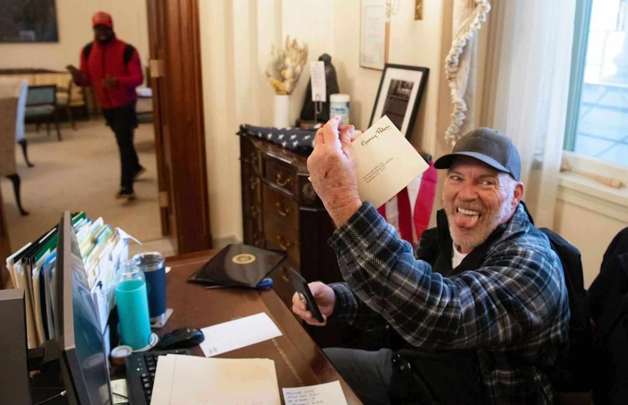 (FILES) Richard Barnett, a supporter of US President Donald Trump, holds a piece of mail as he sits inside the office of US Speaker of the House Nancy Pelosi after protestors breached the US Capitol in the US Capitol in Washington, DC, January 6, 2021. - Demonstrators breeched security and entered the Capitol as Congress debated the 2020 presidential election Electoral Vote Certification. (Photo by SAUL LOEB / AFP)