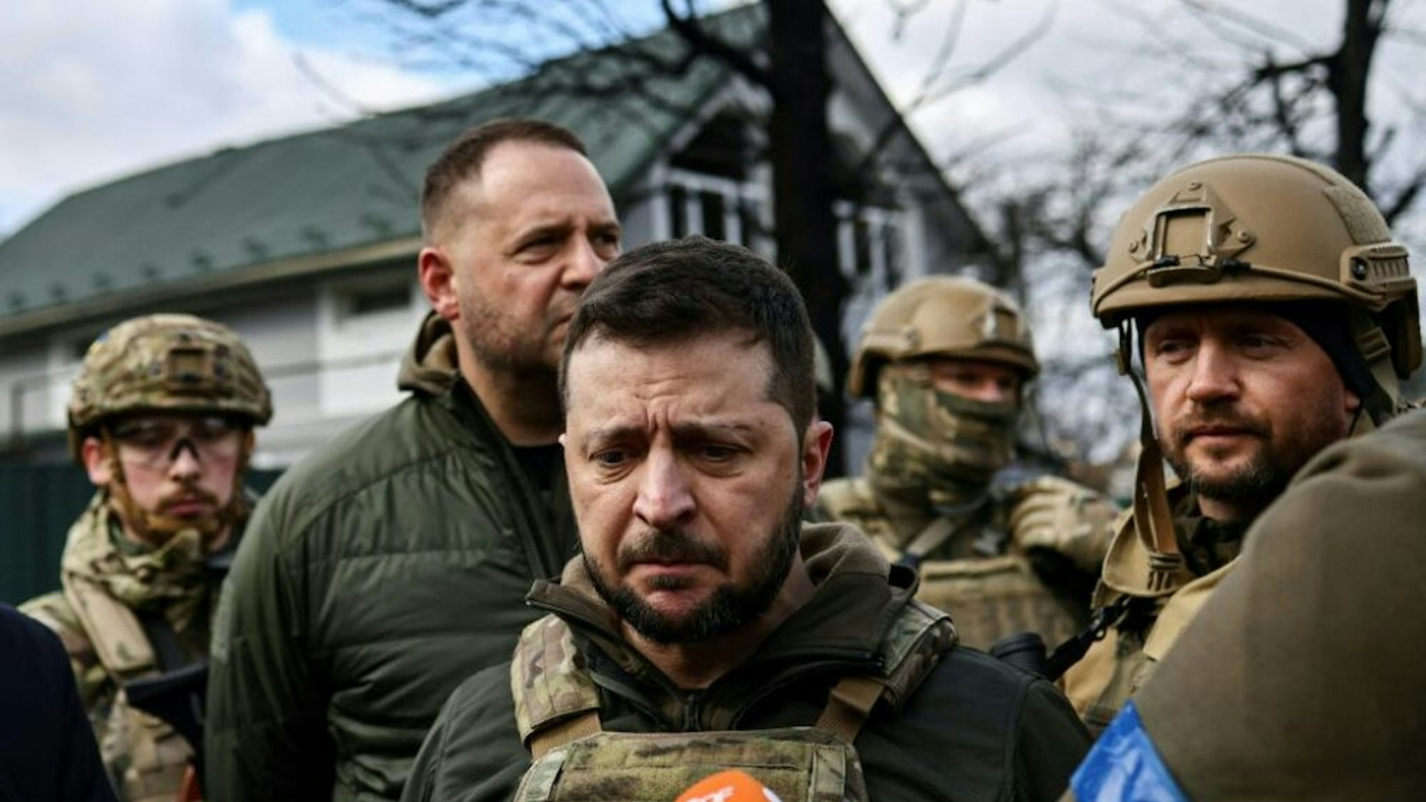 Ukrainian President Volodymyr Zelensky (C) speaks to the press in the town of Bucha, northwest of the Ukrainian capital Kyiv, on April 4, 2022. - Ukraine's President Volodymyr Zelensky said on April 3, 2022 the Russian leadership was responsible for civilian killings in Bucha, outside Kyiv, where bodies were found lying in the street after the town was retaken by the Ukrainian army.