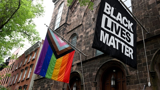 NEW YORK, NEW YORK - JUNE 13: A progress pride flag and a Black Lives Matter flag are displayed outside a church on June 13, 2021 in the Brooklyn Borough of New York City. On May 19, 2021 New York Governor Andrew Cuomo lifted all coronavirus pandemic restrictions paving the way for most Pride month events to resume normally. New York City Pride weekend will be June 25th-27th.