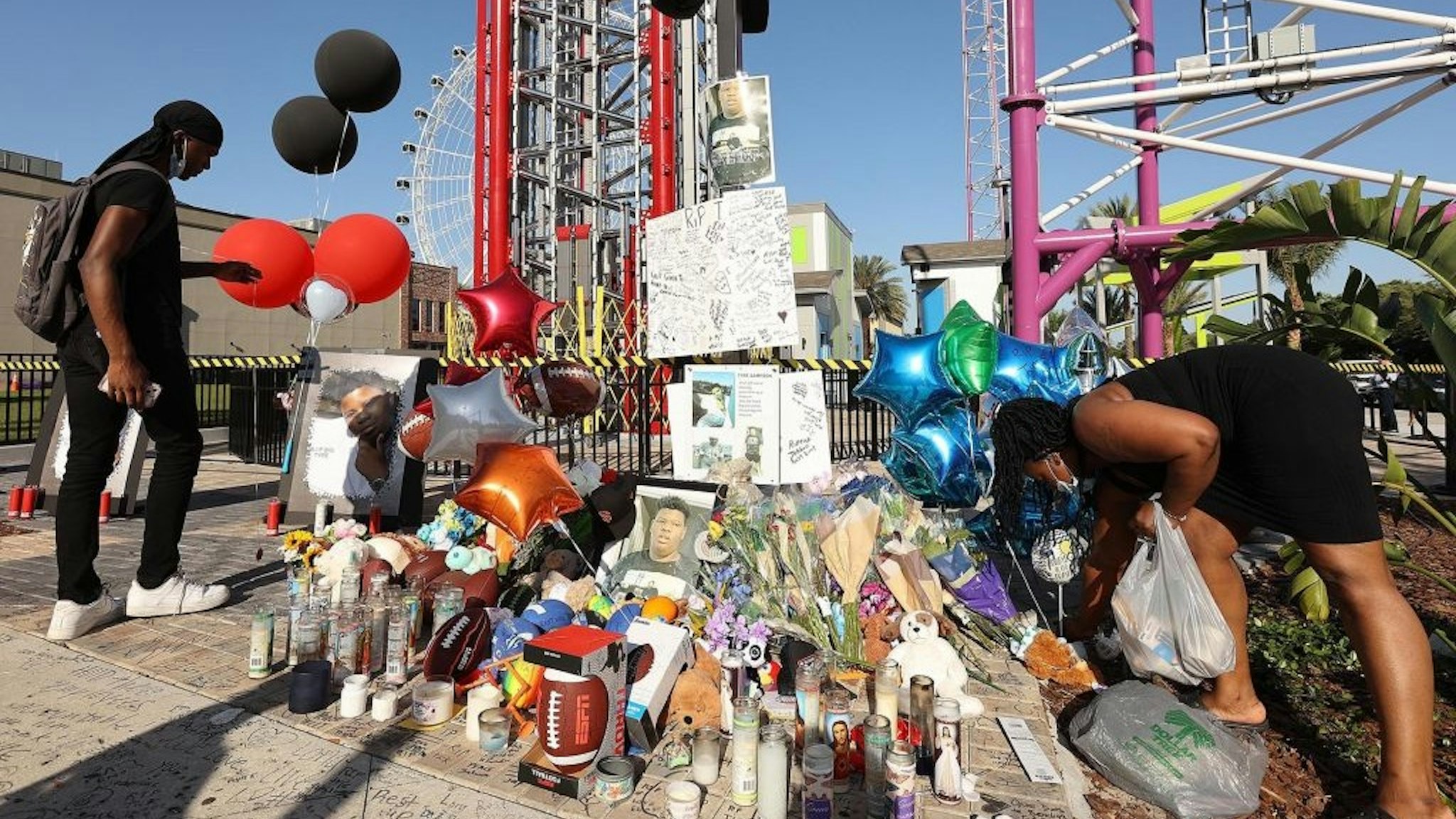 Family members and friends of Tyre Sampson leave flowers and other items at a vigil in front of the Orlando Free Fall drop tower in ICON Park in Orlando, Florida, on Monday, March 28, 2022.
