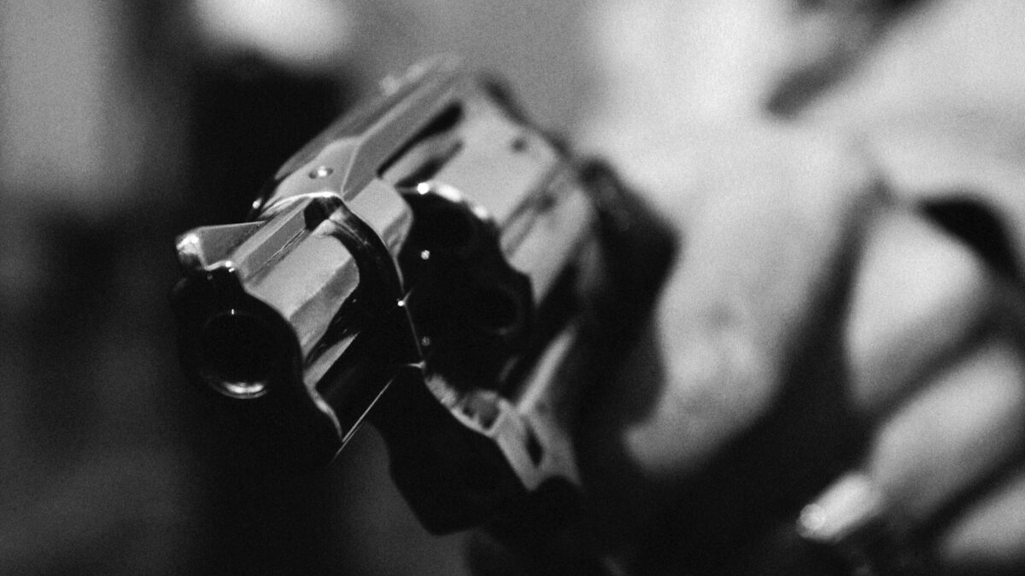 Hand holding gun, close-up, b&w