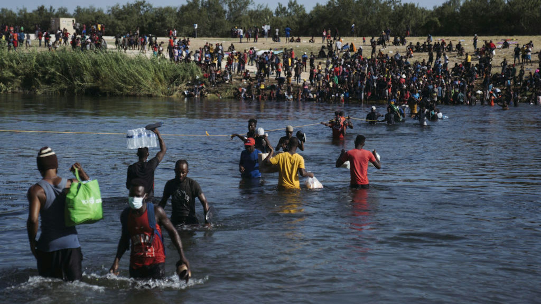Migrants cross the Rio Grande River near the Del Rio-Acuna Port of Entry in Acuna, Coahuila state, Mexico, on Monday, Sept. 20, 2021. The U.S. flew Haitians camped in a Texas border town back to their homeland Sunday and tried blocking others from crossing the border from Mexico in a massive show of force that signaled the beginning of what could be one of America's swiftest, large-scale expulsions of migrants or refugees in decades, reports the Associated Press. Photographer: Eric Thayer/Bloomberg