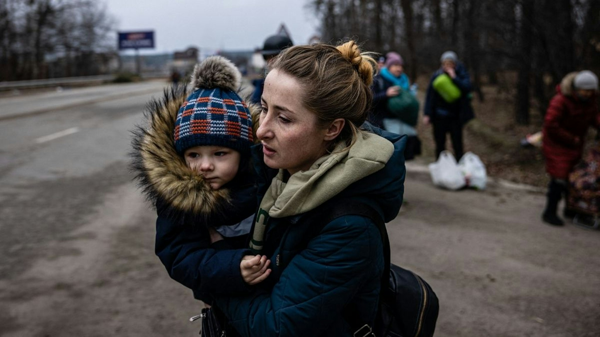 A woman carries her child as they flee the city of Irpin, northwest of Kyiv, on March 7, 2022.
