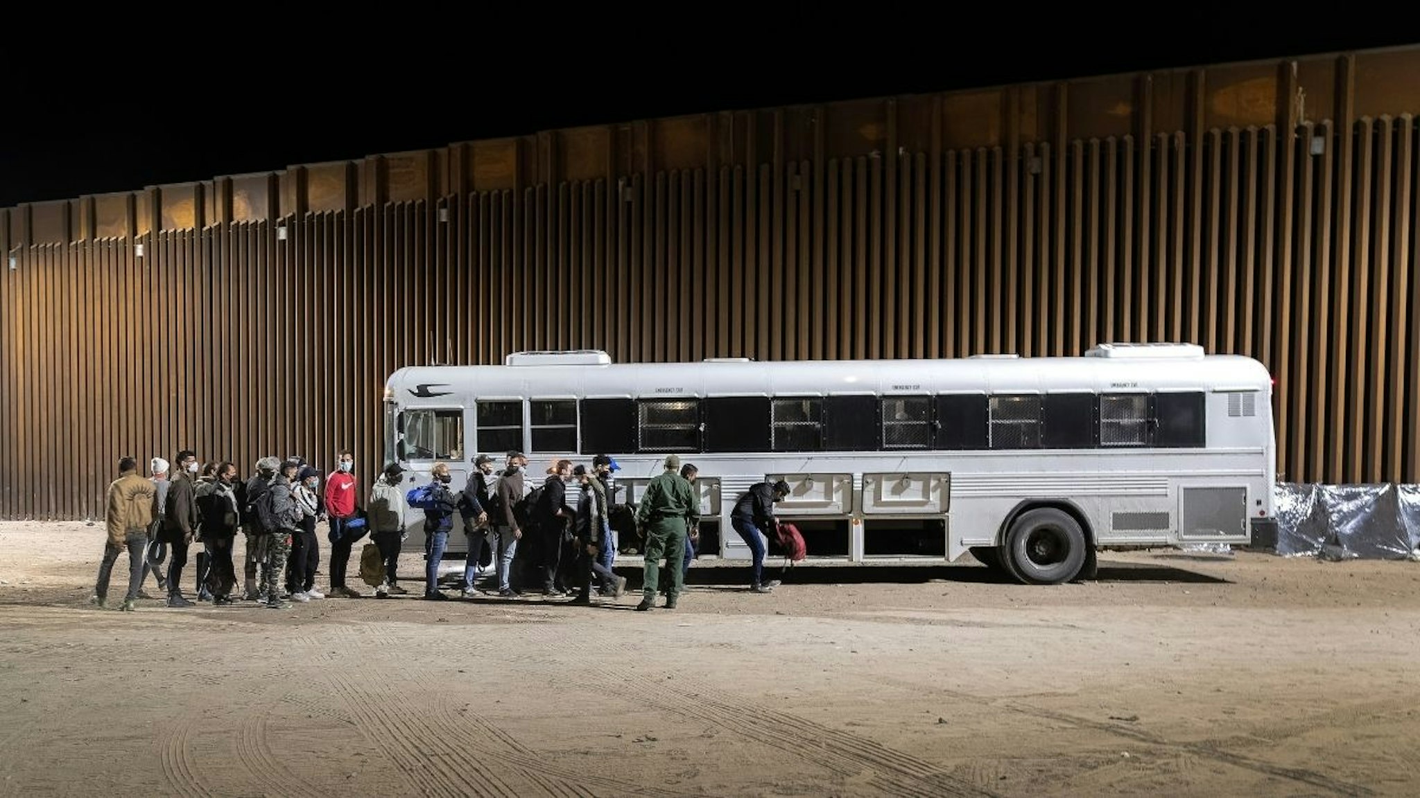 Border Patrol agents load immigrants into a bus for transport to a detention facility on December 08, 2021 through the city of Yuma, Arizona.
