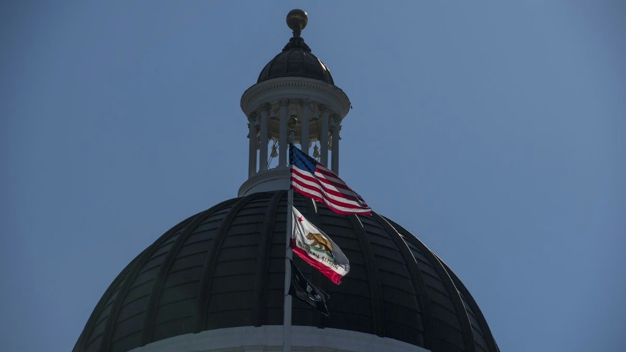 The American, California State, and POW/MIA flags fly in front of the California State Capitol building in Sacramento, California, U.S., on Thursday, March 30, 2017.
