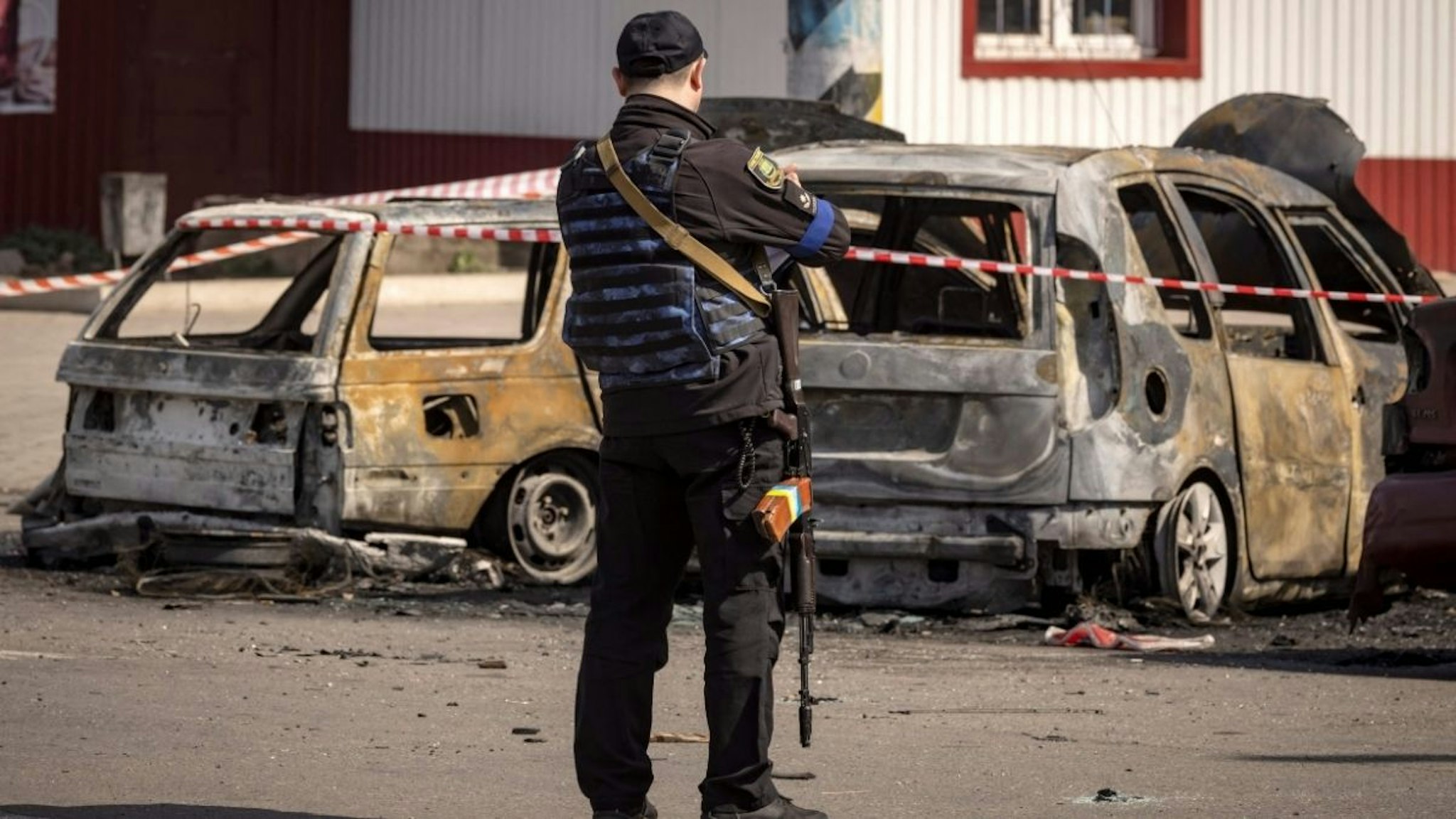 A Ukrainian police stands by calcinated cars outside a train station in Kramatorsk, eastern Ukraine, that was being used for civilian evacuations, after it was hit by a rocket attack killing at least 35 people, on April 8, 2022.