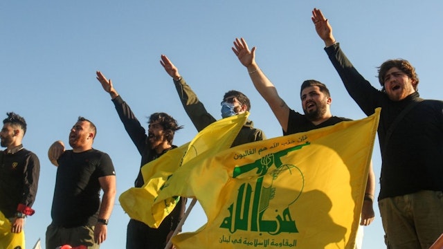 Supporters of the Lebanese Shiite movement Hezbollah perform a salute as they stand behind motorcycles carrying the group's flags in the southern Lebanese district of Marjayoun on the border with Israel on May 25, 2020.