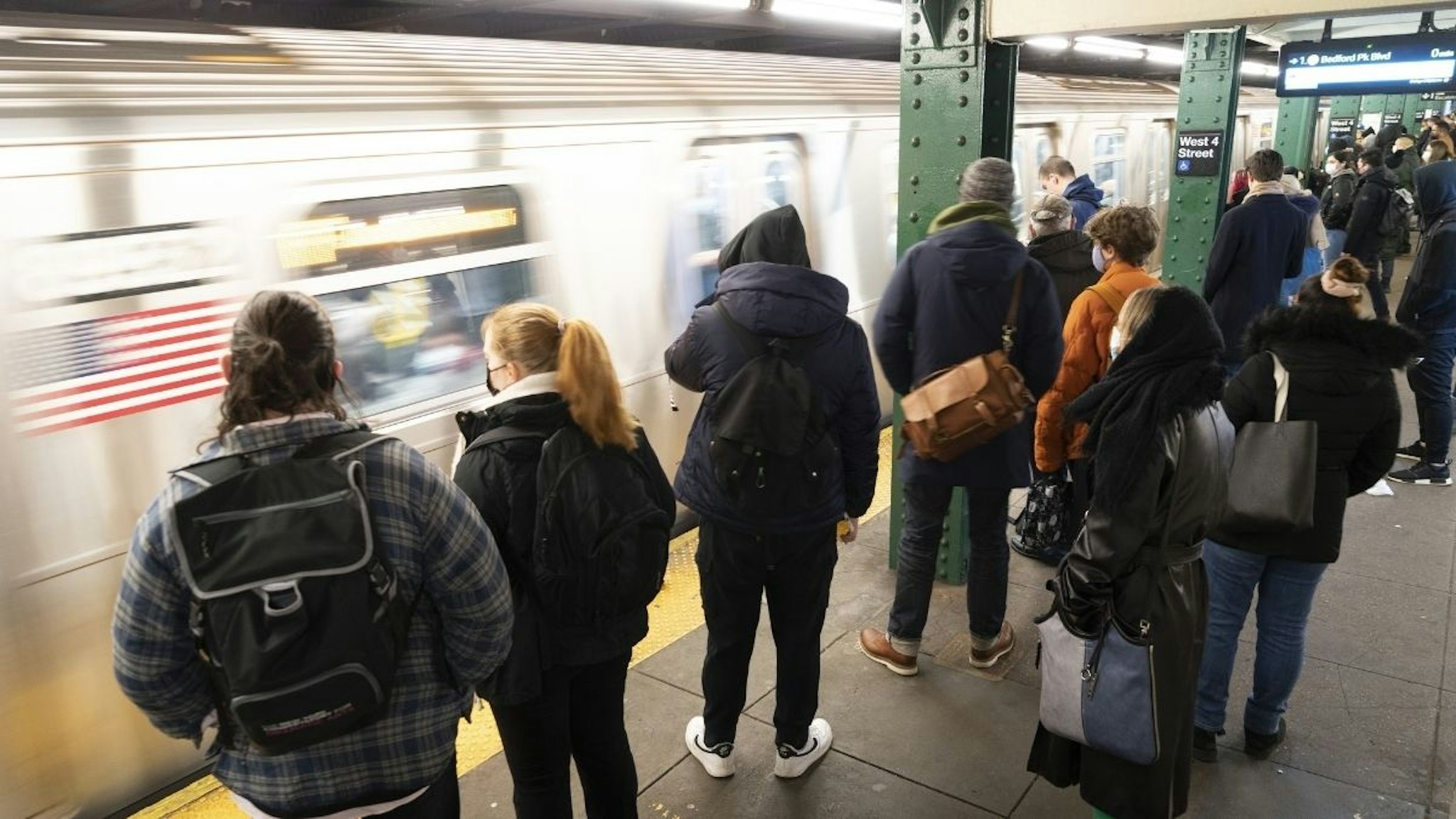 Commuters wait on the platform to board a subway at a station in New York, U.S., on Monday, March 28, 2022.