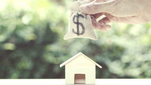Saving money, home loan, mortgage, a property investment for future concept. - stock photo Saving money, home loan, mortgage, a property investment for future concept : A man hand putting moneybag over small residence house and with green nature background. A sustainable investment. Indysystem via Getty Images