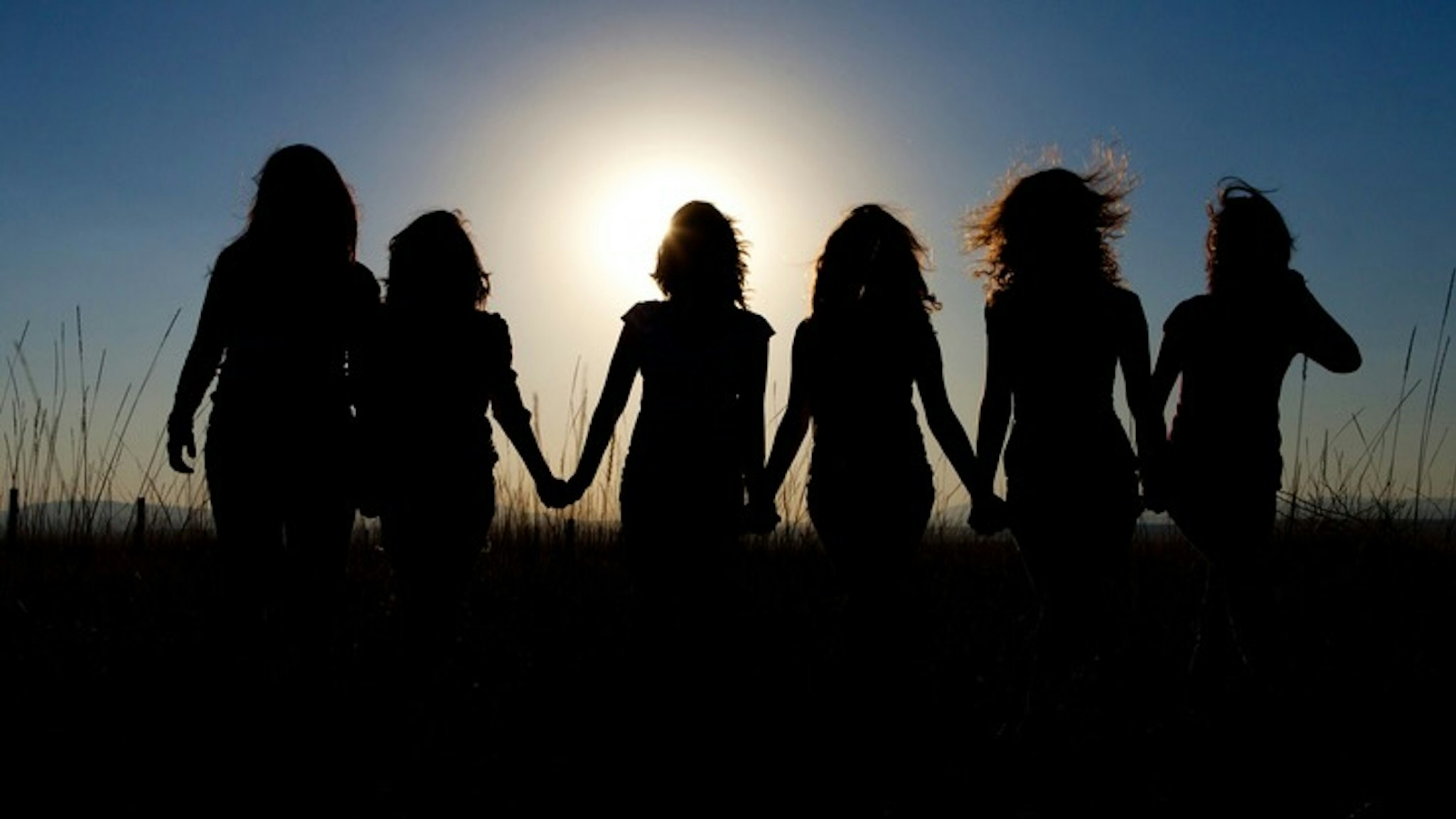 Silhouettes of girls walking in tall grass - stock photo Holly Wilmeth via Getty Images