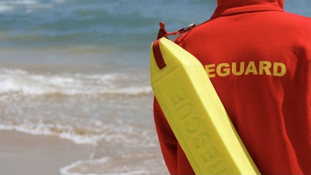 Baywatch Lifeguard With Float At A Beach - stock photo A lifeguard complete with rescue float monitors their beach dmbaker via Getty Images