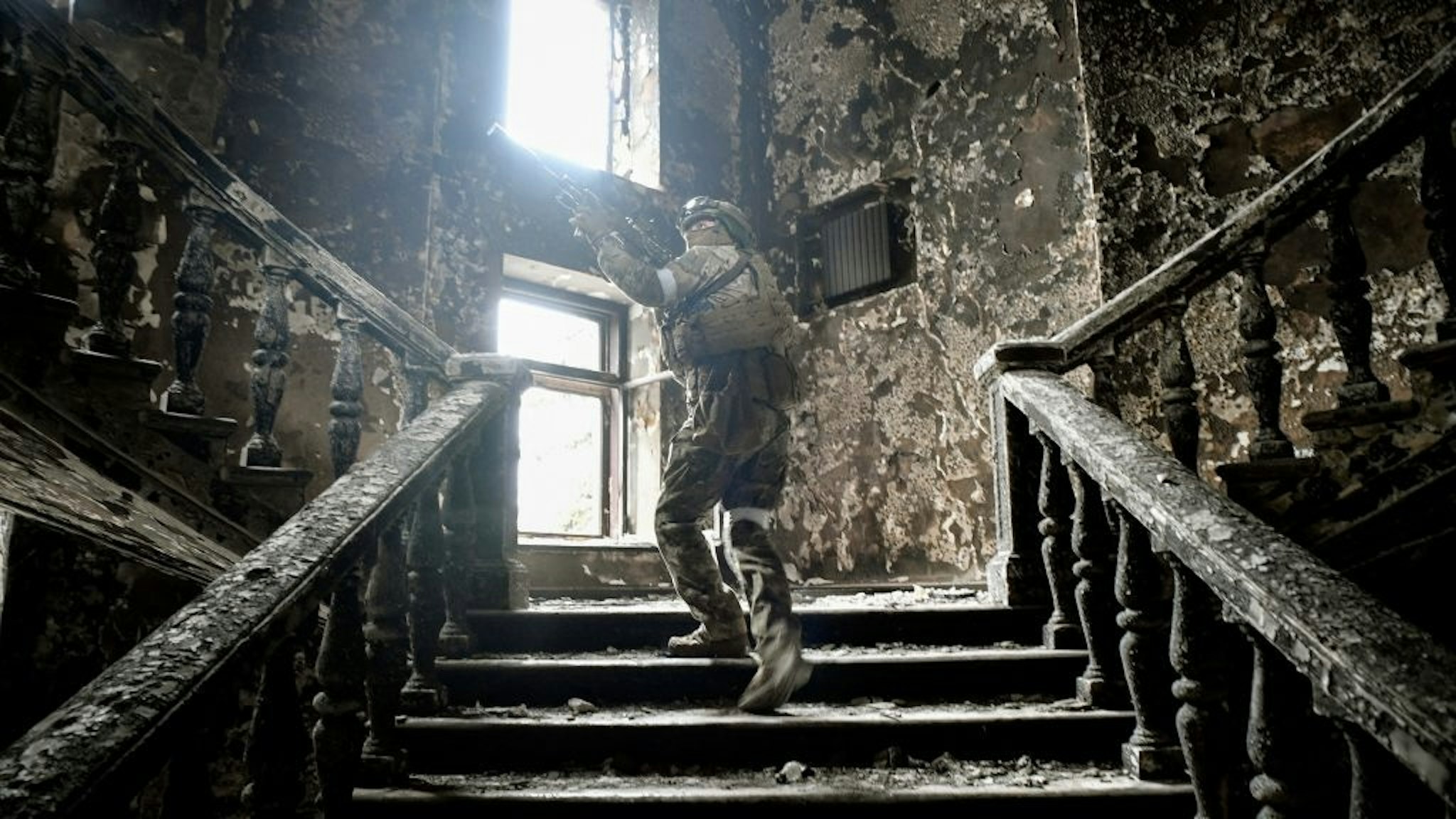 TOPSHOT-UKRAINE-RUSSIA-CONFLICT TOPSHOT - A Russian soldier climbs stairs at the Mariupol drama theatre, hit on March 16 by an airstrike, on April 12, 2022 in Mariupol, as Russian troops intensify a campaign to take the strategic port city, part of an anticipated massive onslaught across eastern Ukraine, while Russia's President makes a defiant case for the war on Russia's neighbour. - *EDITOR'S NOTE: This picture was taken during a trip organized by the Russian military.* (Photo by Alexander NEMENOV / AFP) (Photo by ALEXANDER NEMENOV/AFP via Getty Images) ALEXANDER NEMENOV / Contributor