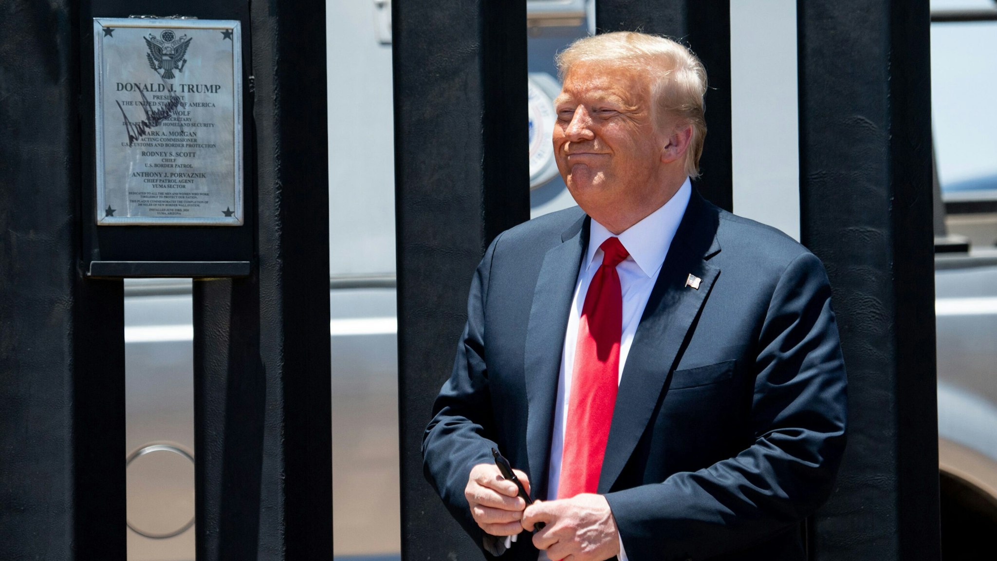 US President Donald Trump smiles after signing a plaque as he participates in a ceremony commemorating the 200th mile of border wall at the international border with Mexico in San Luis, Arizona, June 23, 2020.