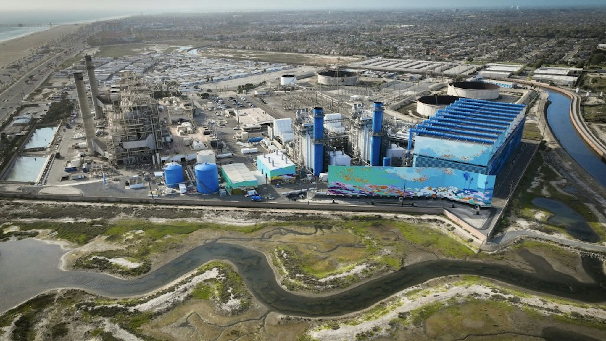 Proposed desalination plant in Huntington Beach Huntington Beach, CA - April 5: An aerial view of the Huntington Beach Wetlands and the Huntington Beach Energy Center, formerly AES Huntington Beach, a natural gas-fired power station that partially uses the power plants existing ocean cooling pipes to tap the Pacific and partially air-cooling, and is the proposed site of the Poseidon desalination plant. Photo taken Tuesday, April 5, 2022. The partially retired Huntington Beach Generating Station consists of four generating units but only unit 2 is still in commercial operation as a legacy unit and has an extension to operate through the end of 2023, issued by the California State Water Boards. Unit 2 runs to support peak demands and has a net output capacity of 225 megawatts. The 644 MW combined cycle gas turbine generator, shown in blue and white, began operation on June 25, 2020. Environmental groups have fought Poseidon, arguing that it is privatizing a public resource, has failed to adapt an old proposal to new state ocean protections from killing sea life and that the company is trying to fill a need that doesnt exist, uses too much natural gas energy. Environmental justice activists say water rates could be raised as much as $6 per month. Supporters say ocean desalination as an inexhaustible, local supply for a region that imports much of its water from increasingly unreliable, distant sources. Another stumbling block for Poseidon is state requirements to mitigate the projects harm to the marine environment. Poseidon would draw 106 million gallons a day of seawater through the huge offshore intake pipe, which would be screened, and use reverse osmosis membranes to rid the seawater of salt and impurities. That process would produce 56 million gallons a day of brine concentrate roughly twice as salty as the ocean which would be dumped back into the Pacific via a 1,500-foot discharge pipe equipped with outfall diffusers to promote mixing and dilution. The intake and discharge operations will take a toll on plankton, which plays a crucial role in the marine food chain, killing an estimated 300,000 microscopic organisms a day. (Allen J. Schaben / Los Angeles Times via Getty Images) Allen J. Schaben / Contributor