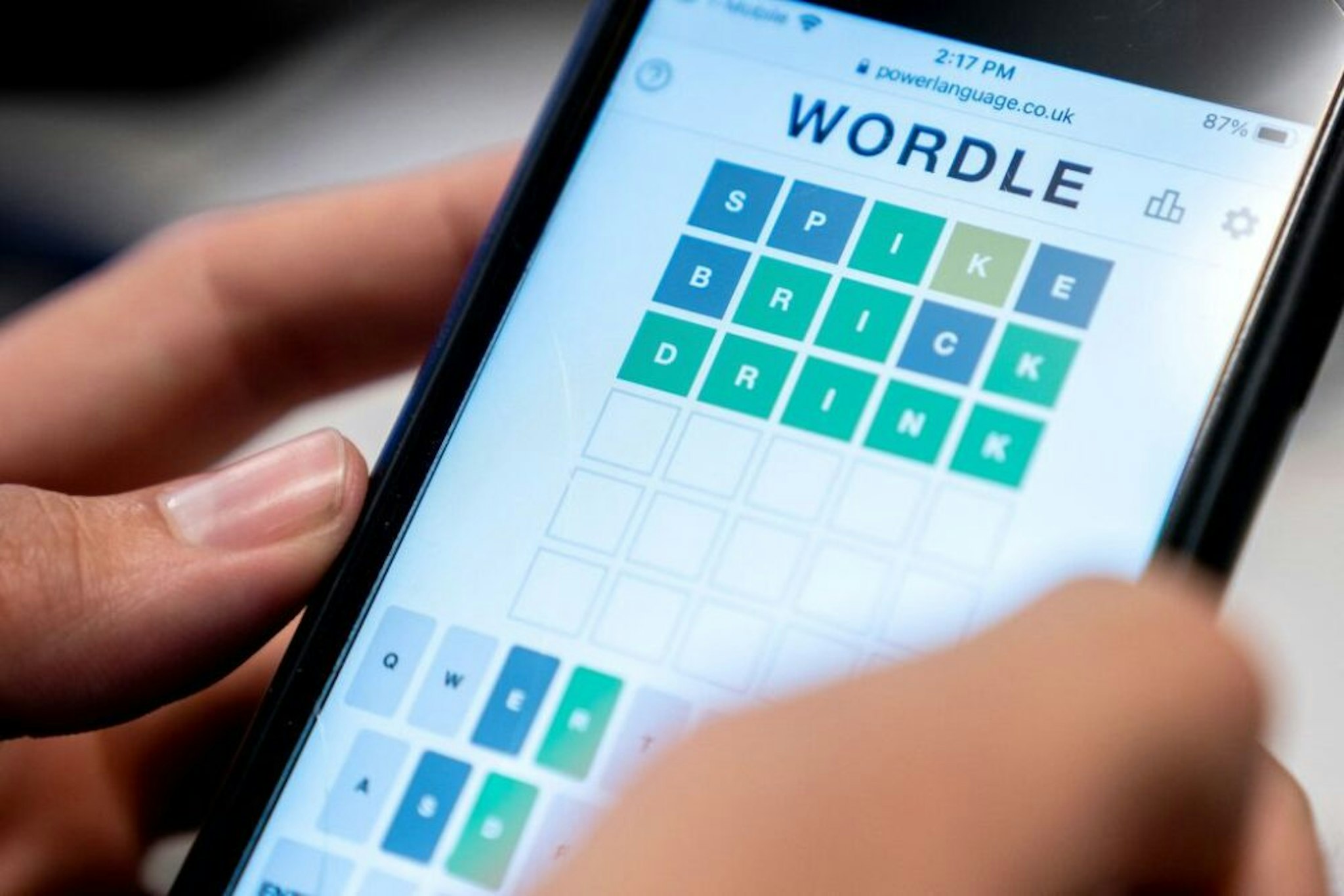 This photo illustration shows a person playing online word game "Wordle" on a mobile phone in Washington, DC on January 11, 2022. - Five letters, six attempts, and only one word per day: the formula for "Wordle" is simple, but for the past few weeks this online game has been stirring up social networks in the United States, and has since been adapted for a French-speaking audience.