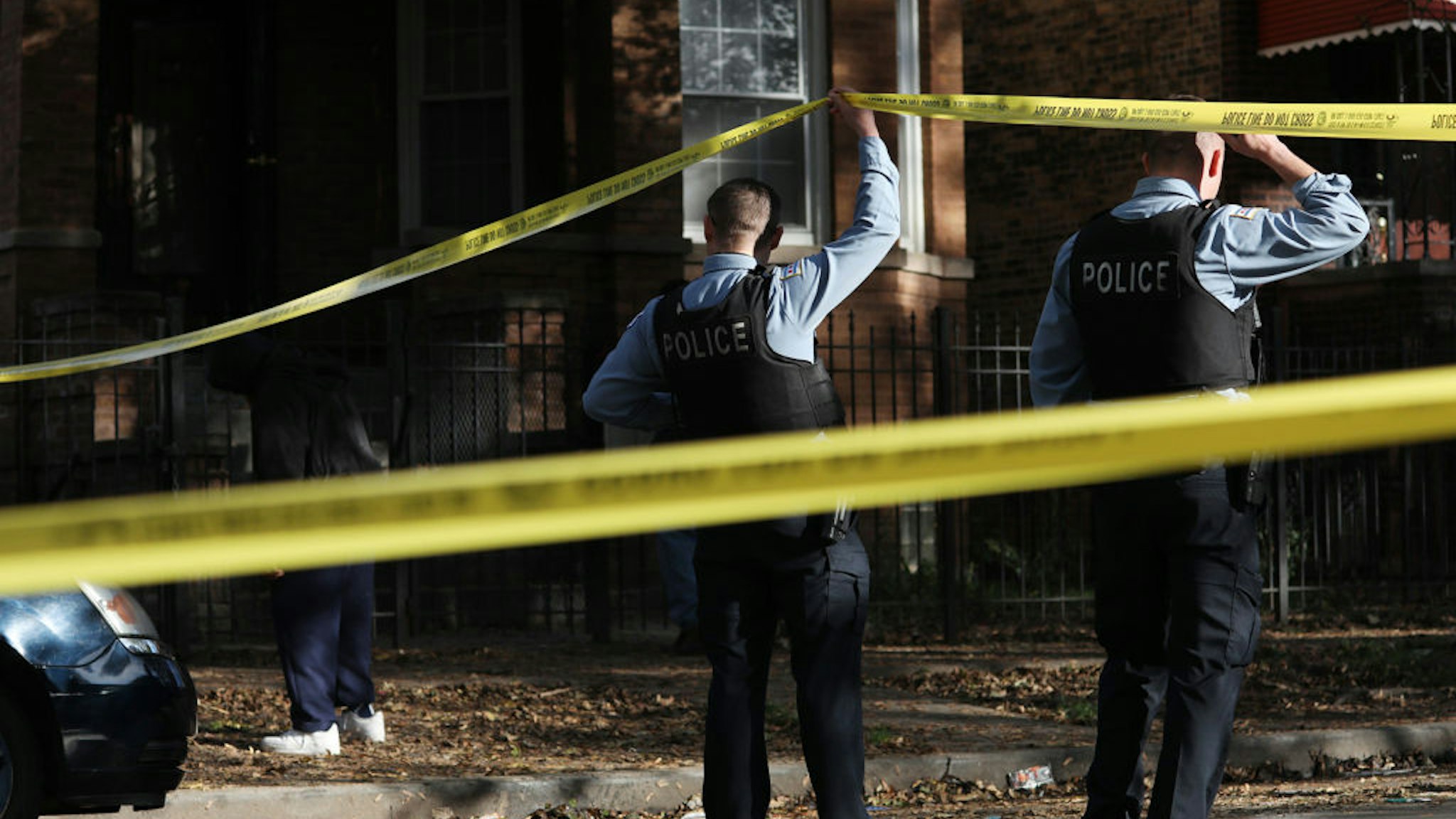 Police officers lift perimeter tape at the scene of a multiple shooting in the 700 block of North Trumbull Avenue in the Humboldt Park neighborhood of Chicago on Oct. 27, 2021, in Chicago. (John J. Kim/Chicago Tribune/Tribune News Service via Getty Images)