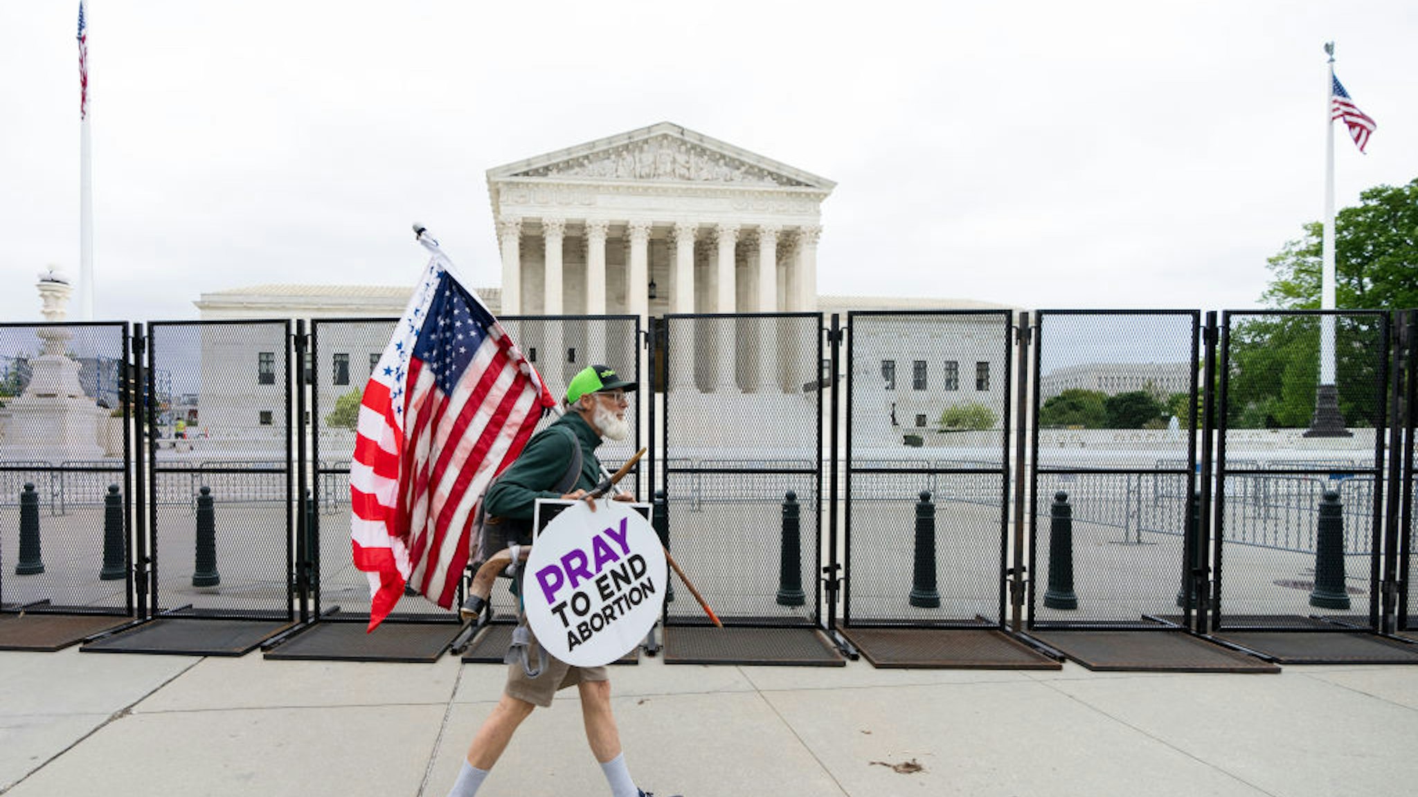 UNITED STATES - MAY 5: A pro-life protester walks by riot fencing surrounding the U.S. Supreme Court in Washington on Thursday, May 5, 2022. The fence was erected overnight in anticipation of ongoing protests following the leaked draft opinion indicating the court will overturn Roe v. Wade. (Bill Clark/CQ-Roll Call, Inc via Getty Images)