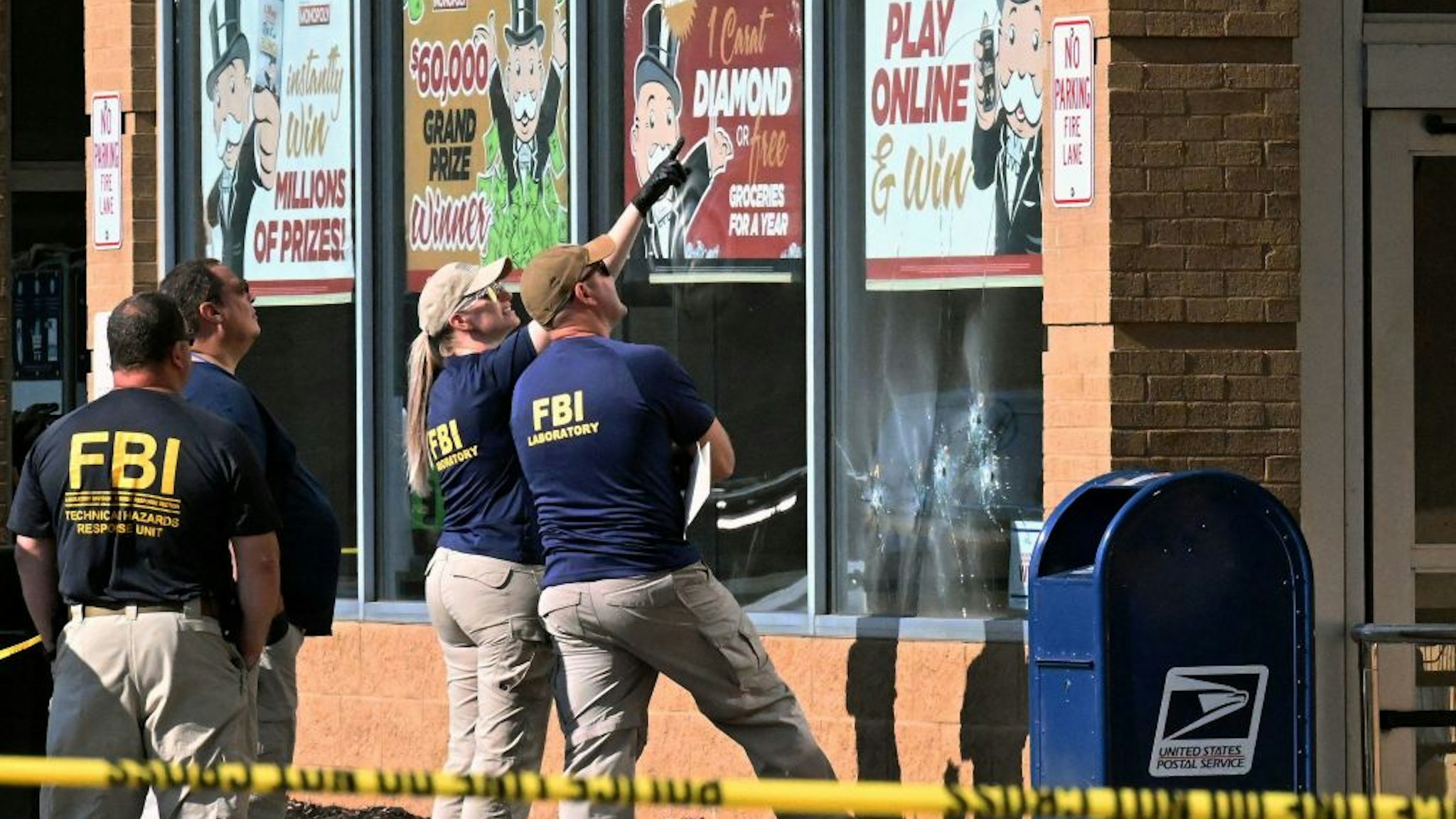 FBI agents look at bullet impacts in a Tops Grocery store in Buffalo, New York, on May 15, 2022, the day after a gunman shot dead 10 people. - Grieving residents from the US city of Buffalo held vigils Sunday after a white gunman who officials have deemed "pure evil" shot dead 10 people at a grocery store in a racially-motivated rampage. (Photo by Usman KHAN / AFP) / The erroneous mention[s] appearing in the metadata of this photo by Usman Ukalizai has been modified in AFP systems in the following manner: byline is [Usman KHAN] instead of [Usman Ukalizai]. Please immediately remove the erroneous mention[s] from all your online services and delete it (them) from your servers. If you have been authorized by AFP to distribute it (them) to third parties, please ensure that the same actions are carried out by them. Failure to promptly comply with these instructions will entail liability on your part for any continued or post notification usage. Therefore we thank you very much for all your attention and prompt action. We are sorry for the inconvenience this notification may cause and remain at your disposal for any further information you may require. (Photo by USMAN KHAN/AFP via Getty Images)
