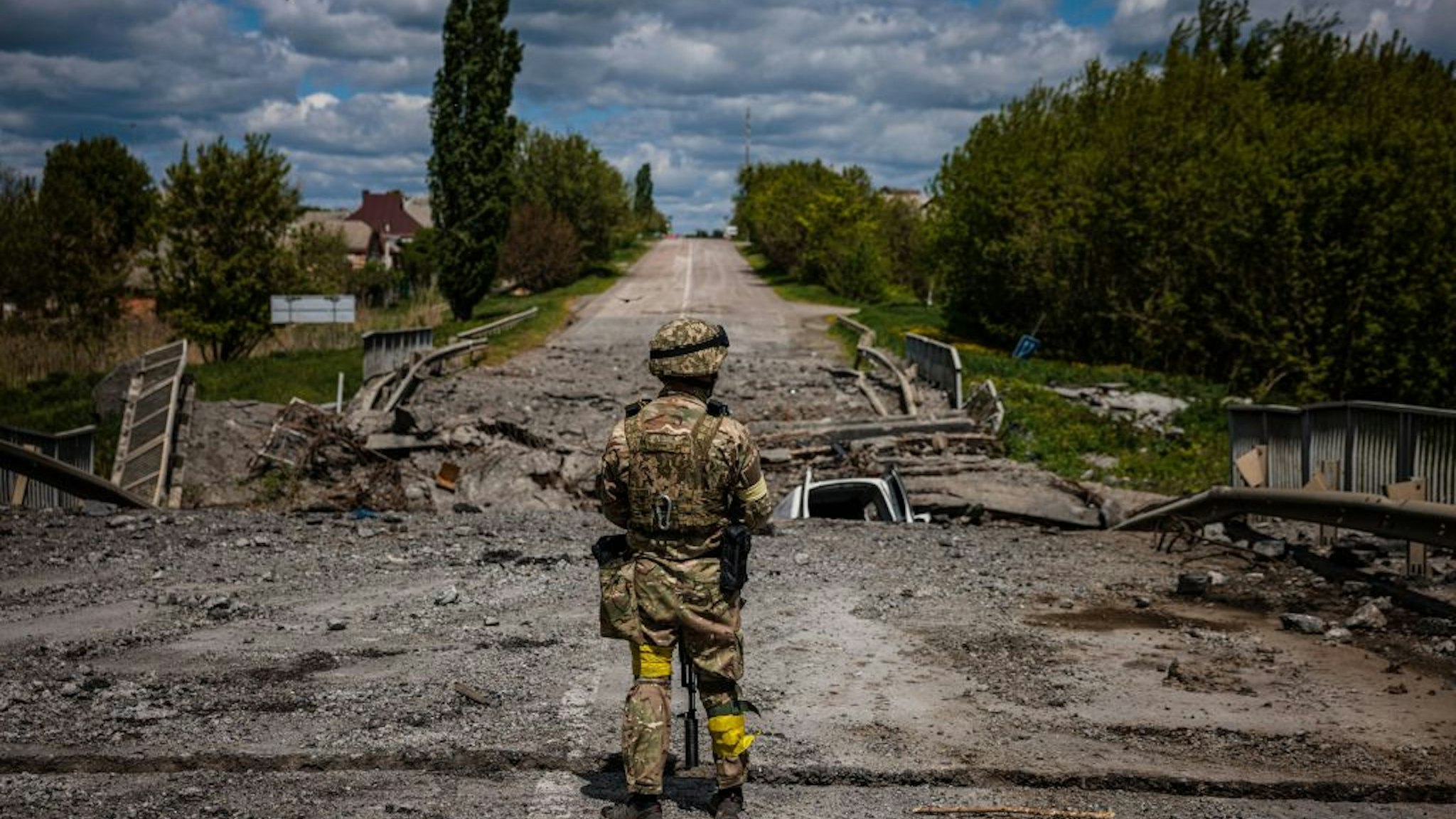 A soldier of the Kraken Ukrainian special forces unit observes the area at a destroyed bridge on the road near the village of Rus'ka Lozova, north of Kharkiv, on May 16, 2022. - Ukraine has said its troops have regained control of territory on the Russian border near the country's second-largest city of Kharkiv, which has been under constant fire since Moscow's invasion began. (Photo by Dimitar DILKOFF / AFP) (Photo by DIMITAR DILKOFF/AFP via Getty Images)