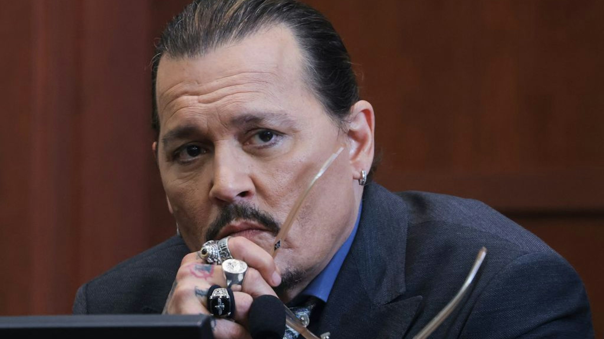 Actor Johnny Depp listens to a question as he testifies in the courtroom during his defamation trial against his ex-wife Amber Heard, at the Fairfax County Circuit Courthouse in Fairfax, Virginia, on May 25, 2022. - Actor Johnny Depp is suing ex-wife Amber Heard for libel after she wrote an op-ed piece in The Washington Post in 2018 referring to herself as a public figure representing domestic abuse. (Photo by EVELYN HOCKSTEIN / POOL / AFP) (Photo by EVELYN HOCKSTEIN/POOL/AFP via Getty Images)