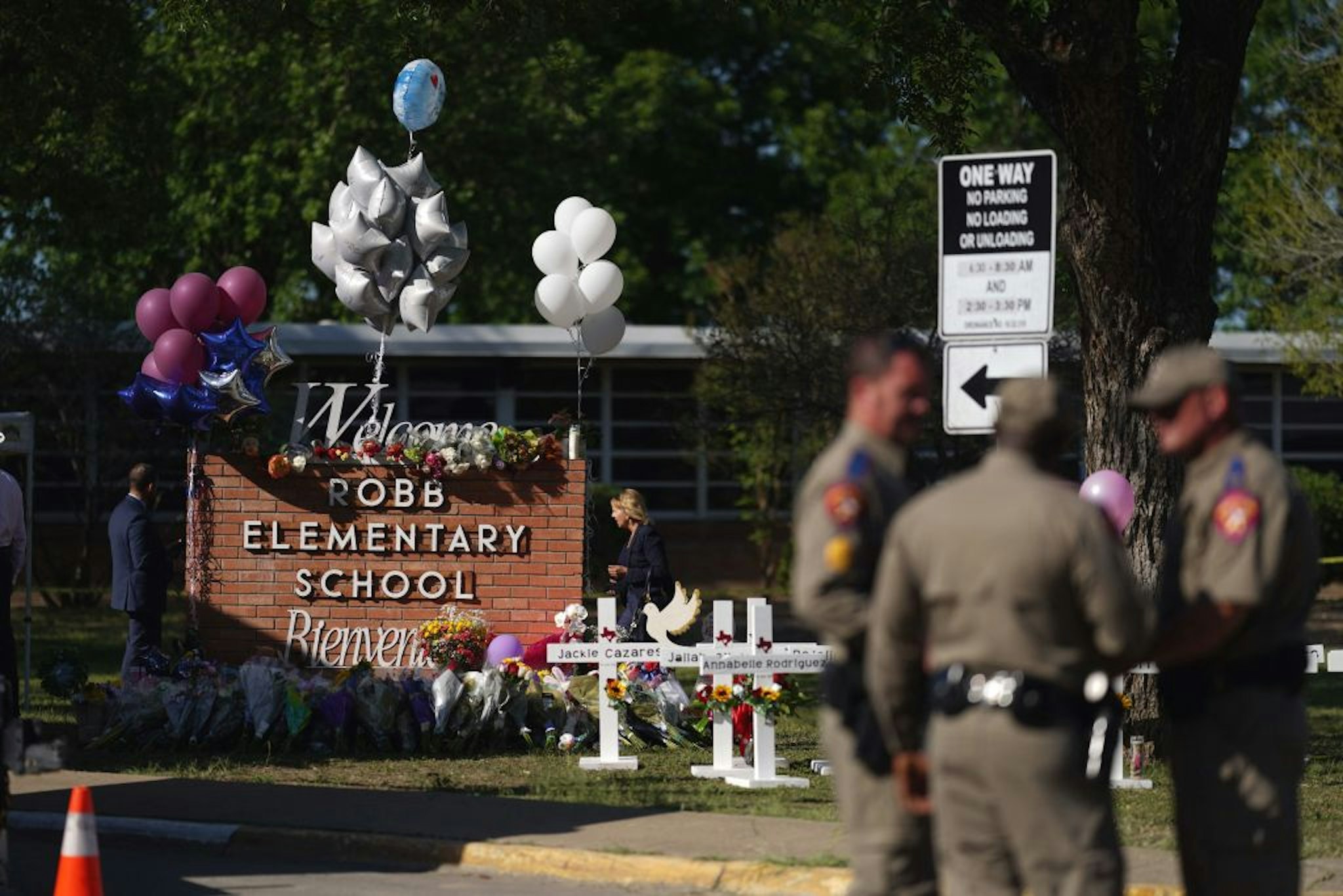 Police officers stand next to a makeshift memorial outside the Robb Elementary School on May 26, 2022 in Uvalde, Texas. - Grief at the massacre of 19 children at the elementary school in Texas spilled into confrontation on May 25, as angry questions mounted over gun control -- and whether this latest tragedy could have been prevented. The tight-knit Latino community of Uvalde on May 24 became the site of the worst school shooting in a decade, committed by a disturbed 18-year-old armed with a legally bought assault rifle. (Photo by allison dinner / AFP) (Photo by ALLISON DINNER/AFP via Getty Images)