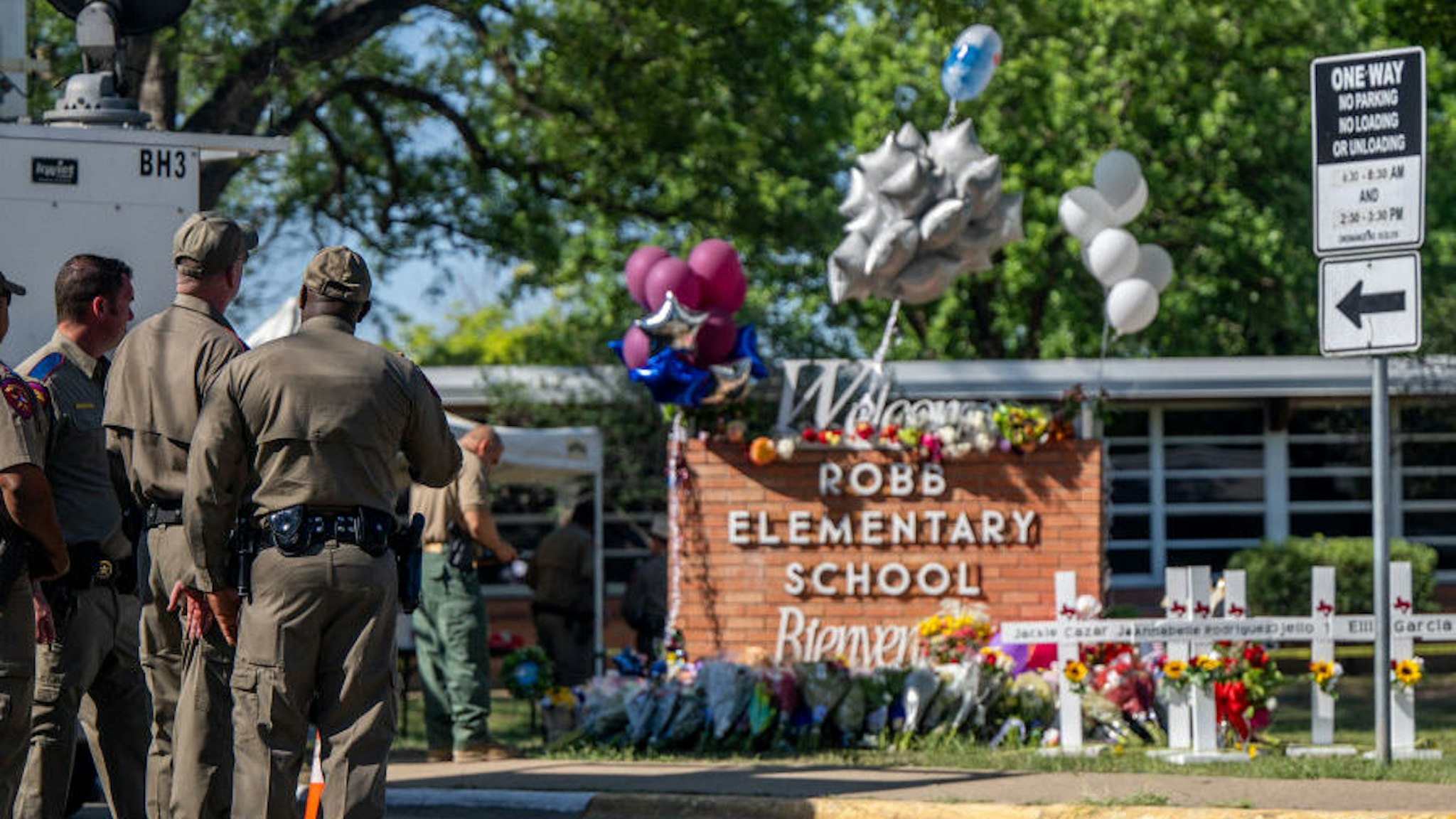 Law enforcement officers stand looking at a memorial following a mass shooting at Robb Elementary School on May 26, 2022 in Uvalde, Texas.