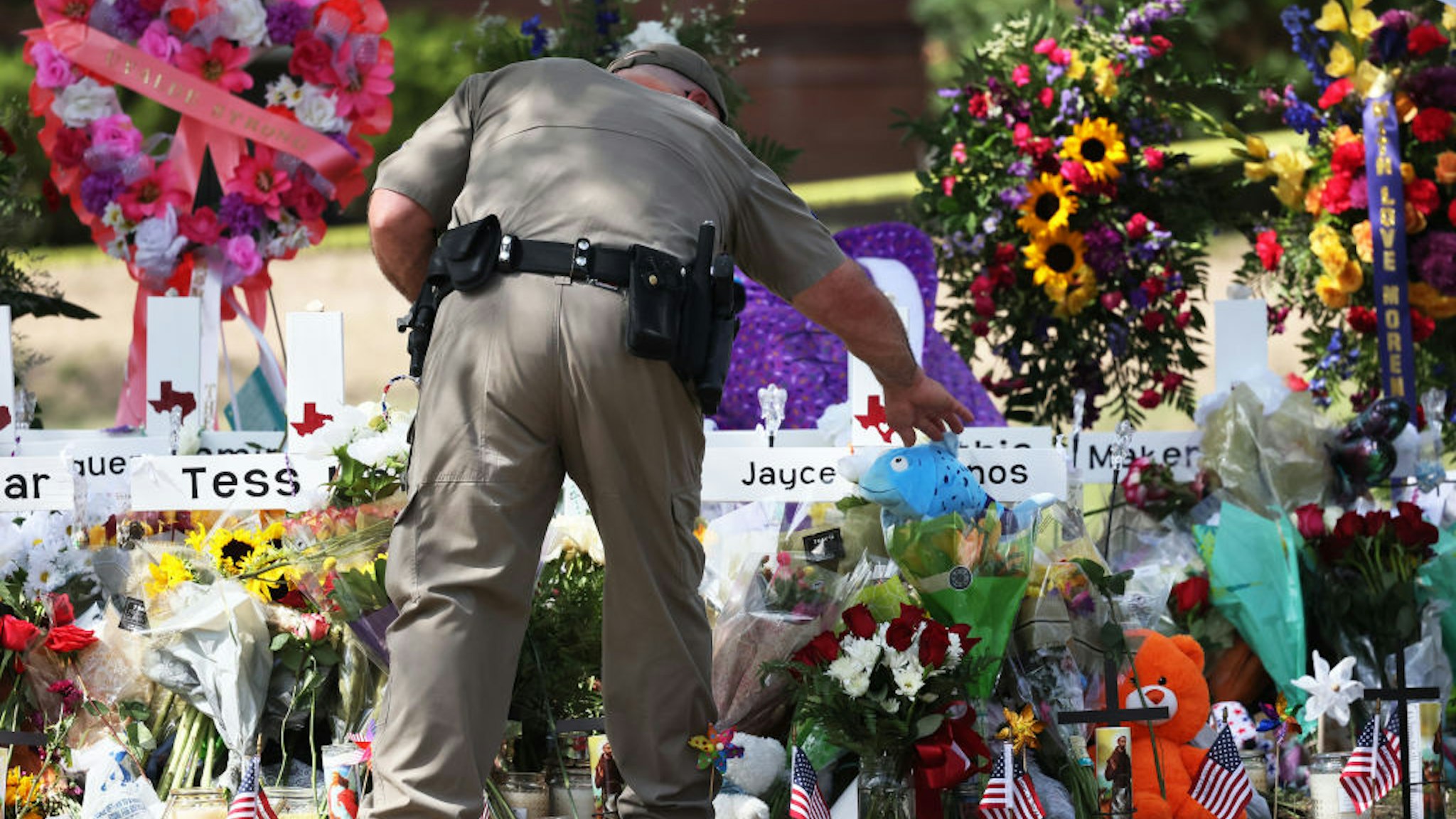 UVALDE, TEXAS - MAY 27: A Texas Highway Patrol Trooper places an item at a memorial for victims of Tuesday's mass shooting at Robb Elementary School on May 27, 2022 in Uvalde, Texas. Steven C. McCraw, Director and Colonel of the Texas Department of Public Safety, held a press conference to give an update on the investigation into Tuesday's mass shooting where 19 children and two adults were killed at Robb Elementary School, and admitted that it was the wrong decision to wait and not breach the classroom door as soon as police officers were inside the elementary school. (Photo by Michael M. Santiago/Getty Images)